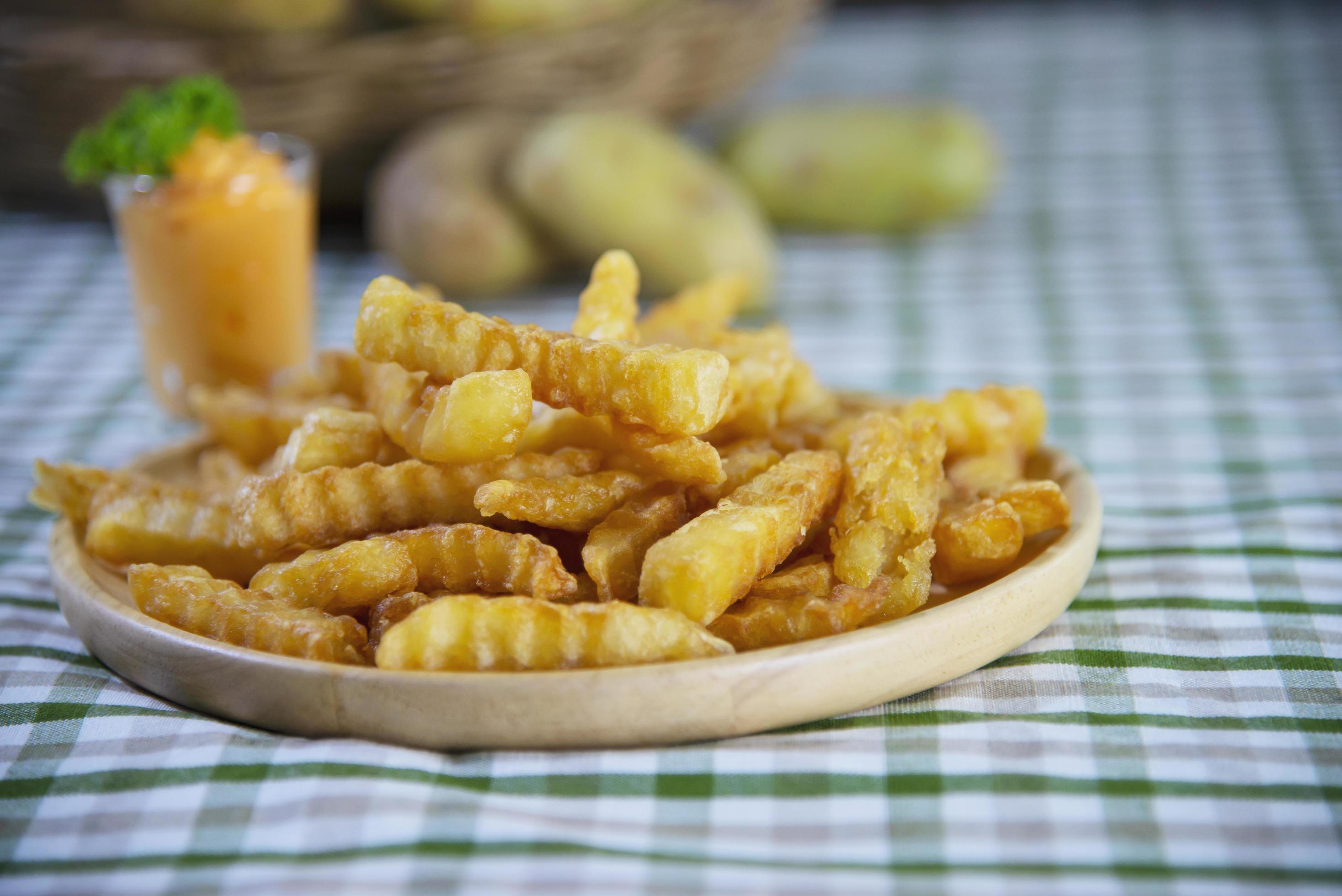 Delicious fried potato on wooden plate with dipped sauce – traditional fast food concept Stock Free