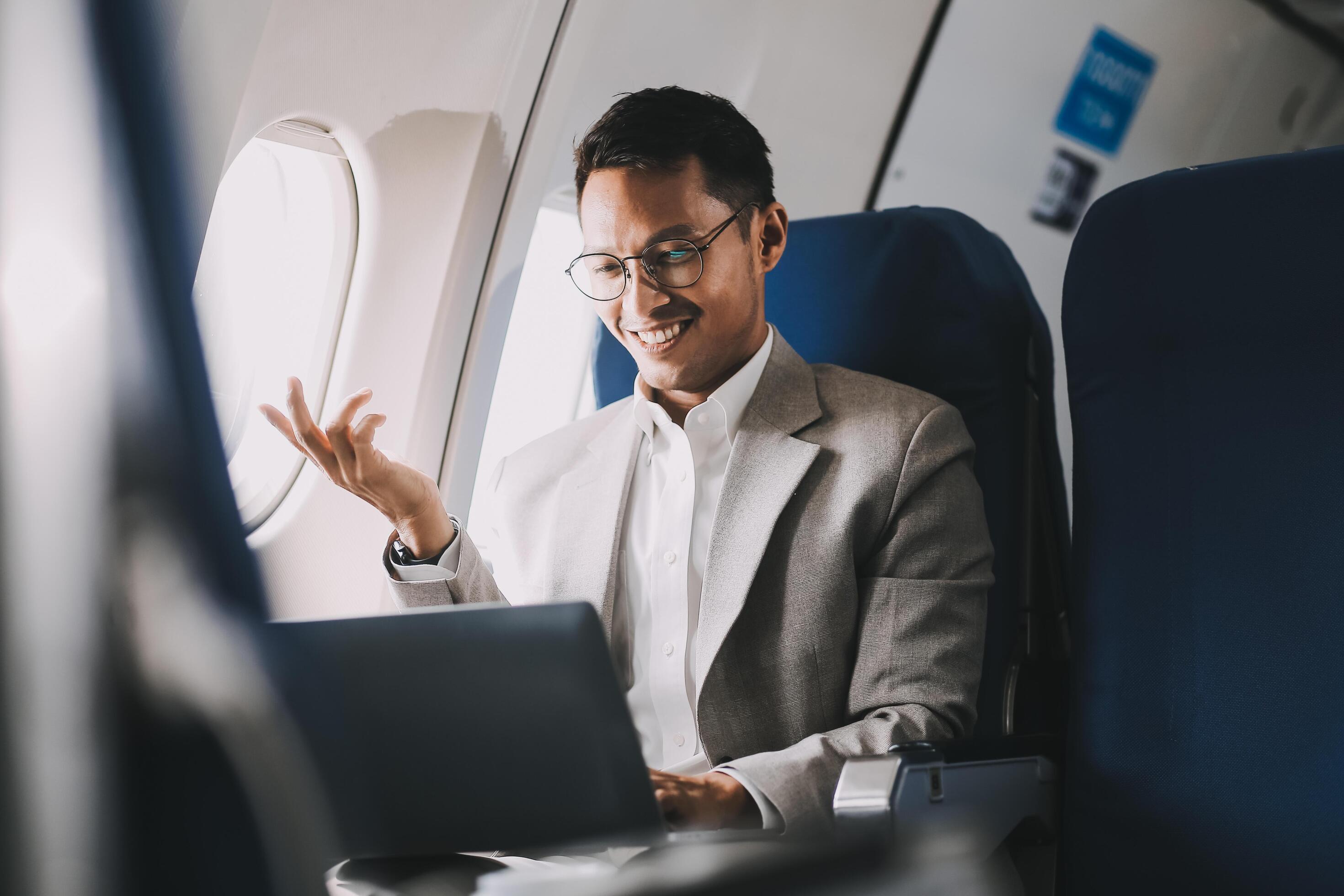 Asian businessman enjoying enjoys a coffee comfortable flight while sitting in the airplane cabin, Passengers near the window. Stock Free