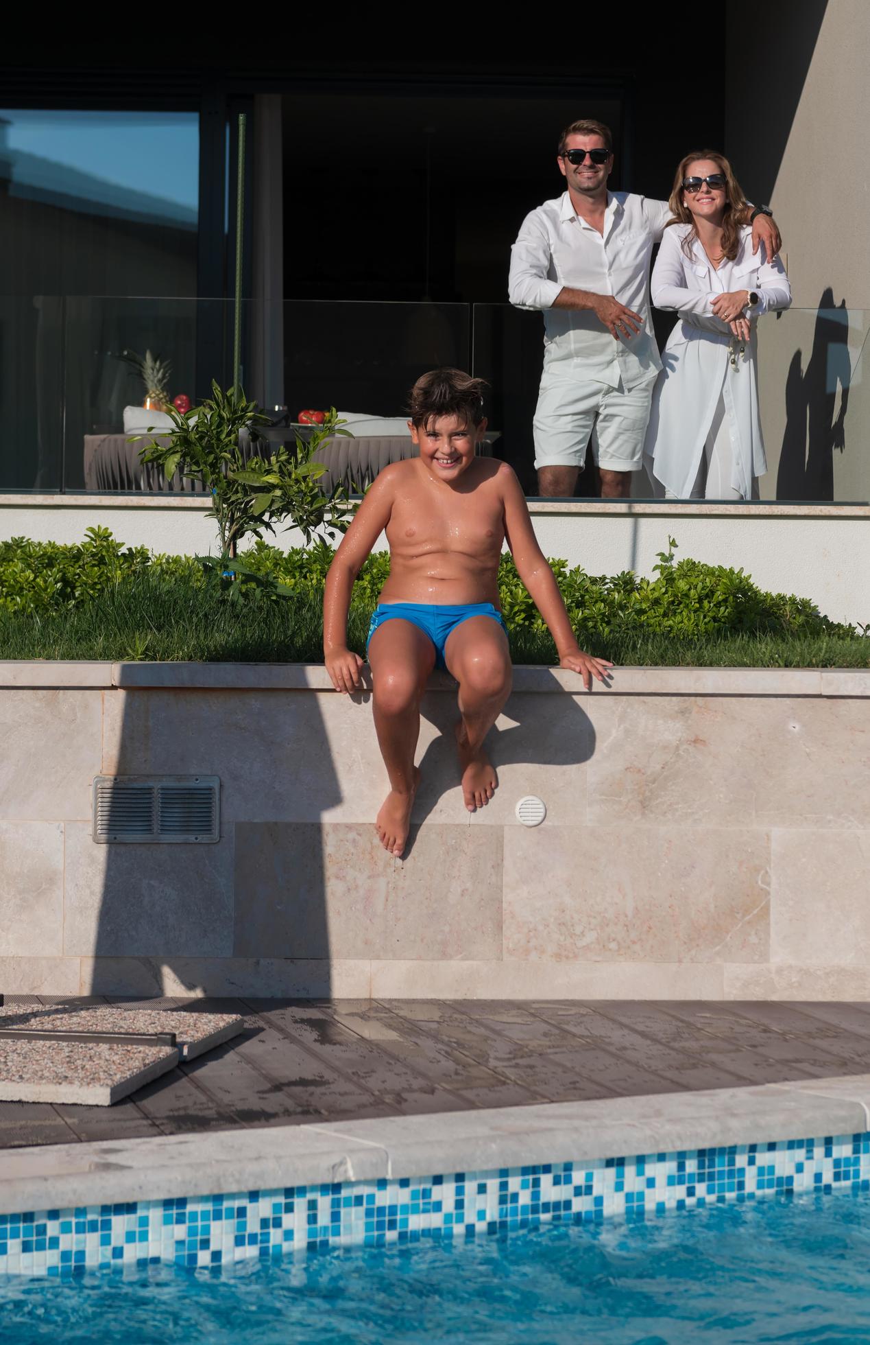 Happy family enjoys vacation in a luxury house with pool. Senior couple spends time with their son during the vacation. Selective focus Stock Free