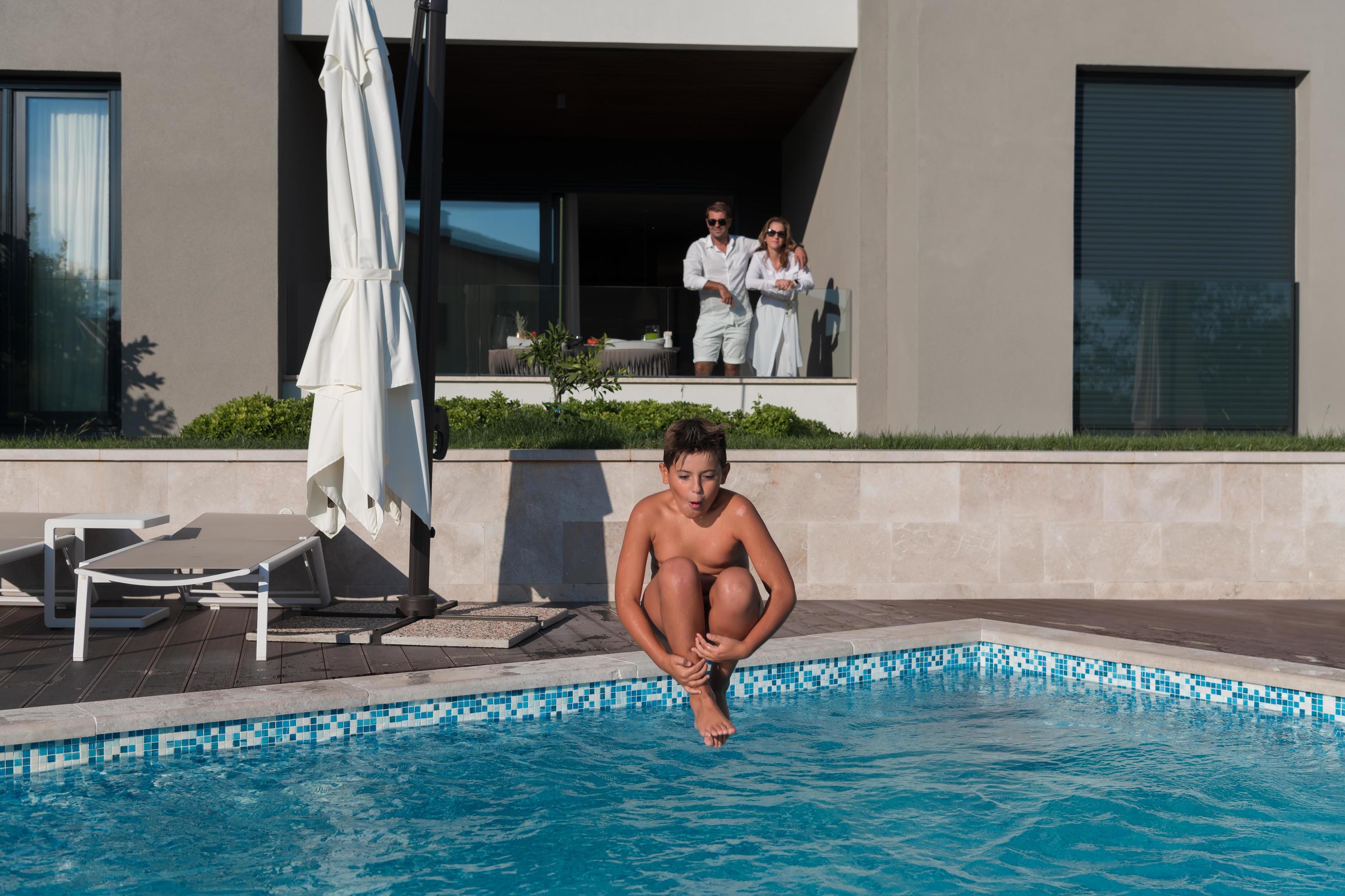 Happy family enjoys vacation in a luxury house with pool. Senior couple spends time with their son during the vacation. Selective focus Stock Free