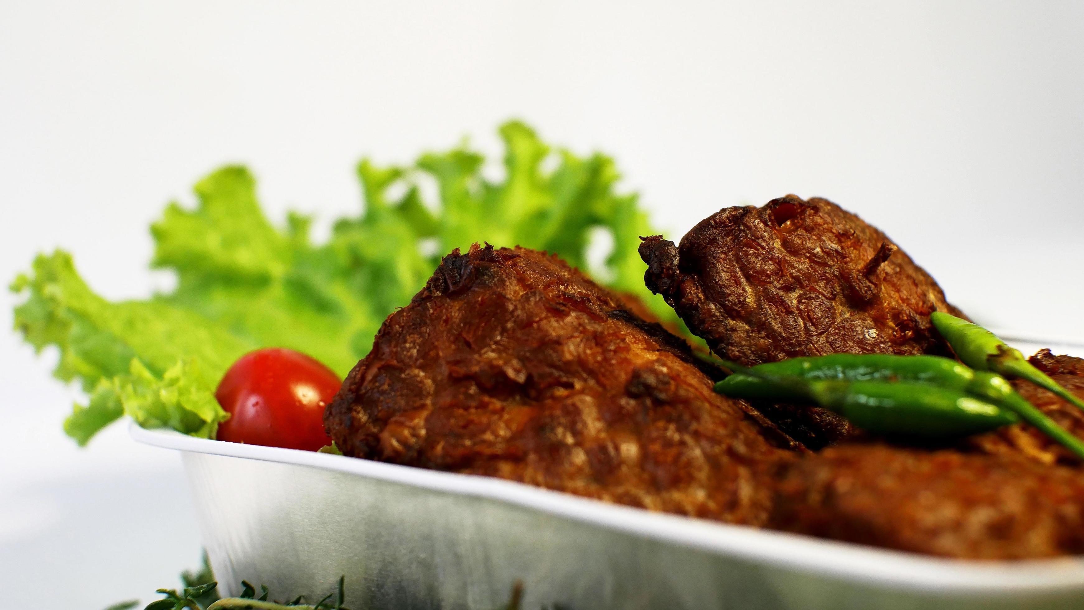 Fried soybean mushrooms, small tomatoes, chilies and salad in one aluminum container. typical indonesian street food on a white background Stock Free