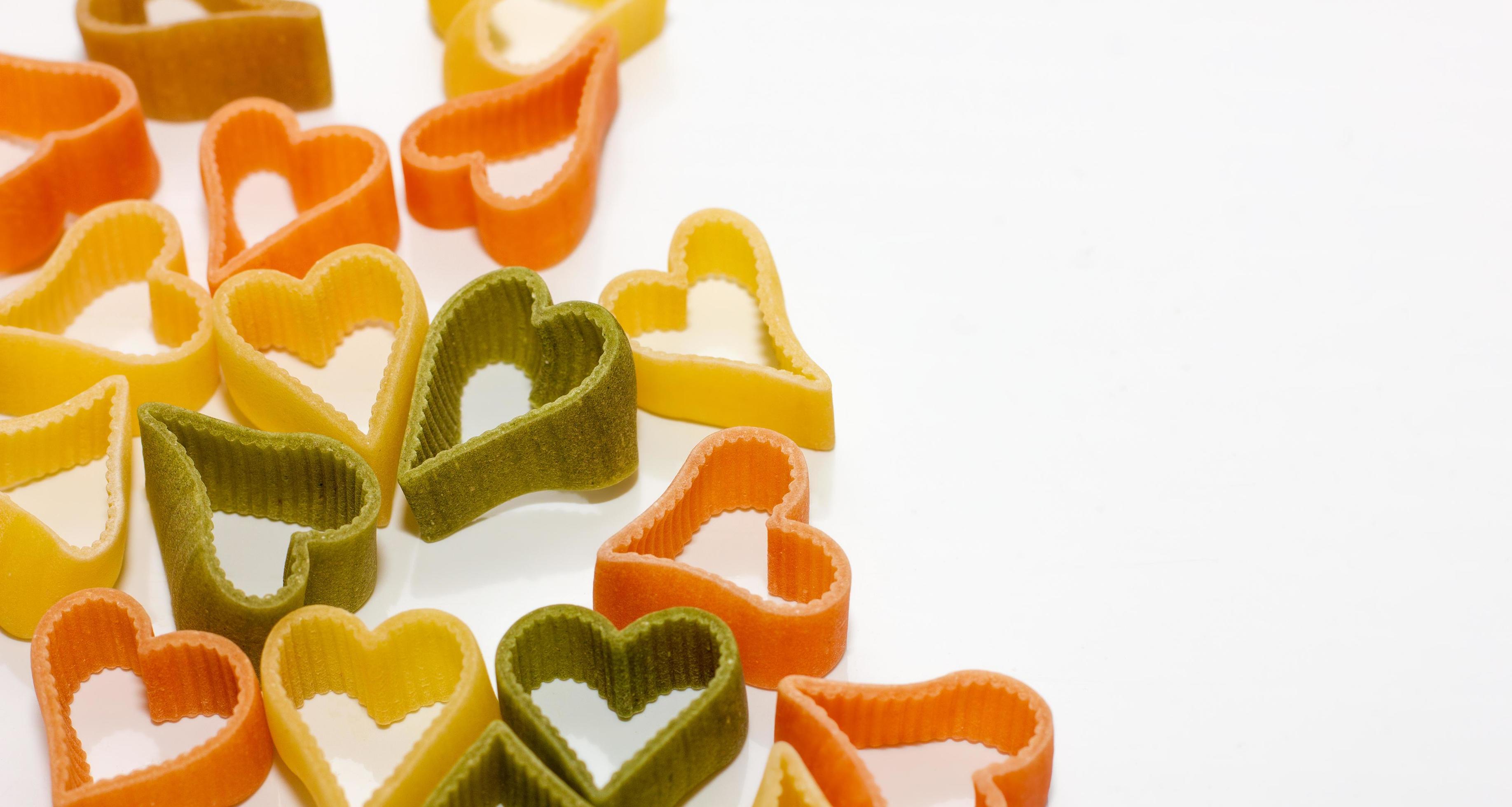 multicolored pasta in the shape of a heart on a white background. holiday and cooking concept, romantic food, Stock Free