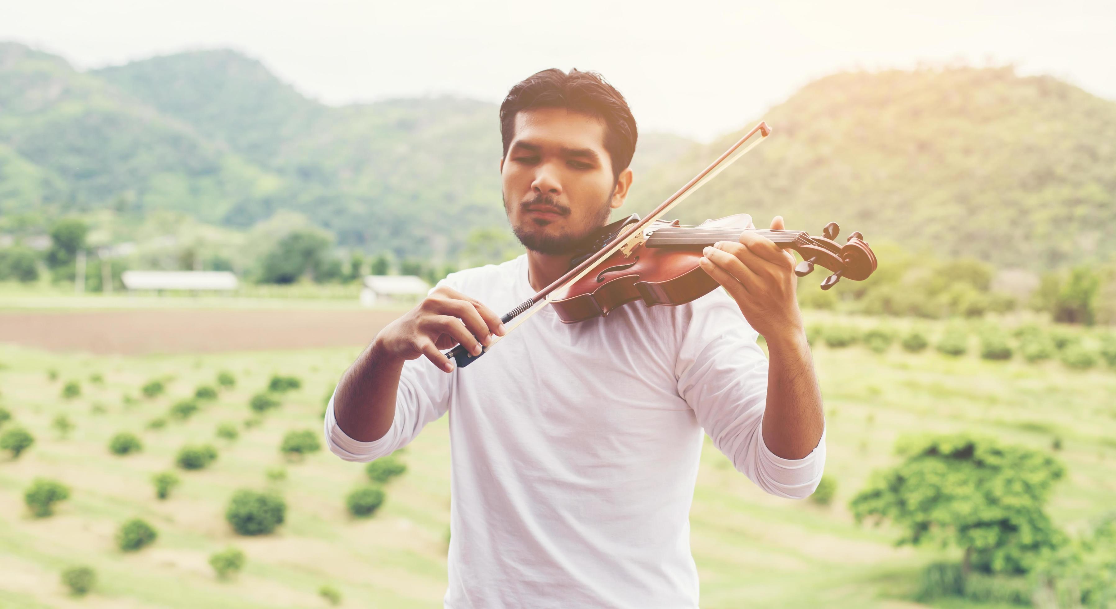 Young hipster musician man playing violin in the nature outdoor lifestyle behind mountain. Stock Free