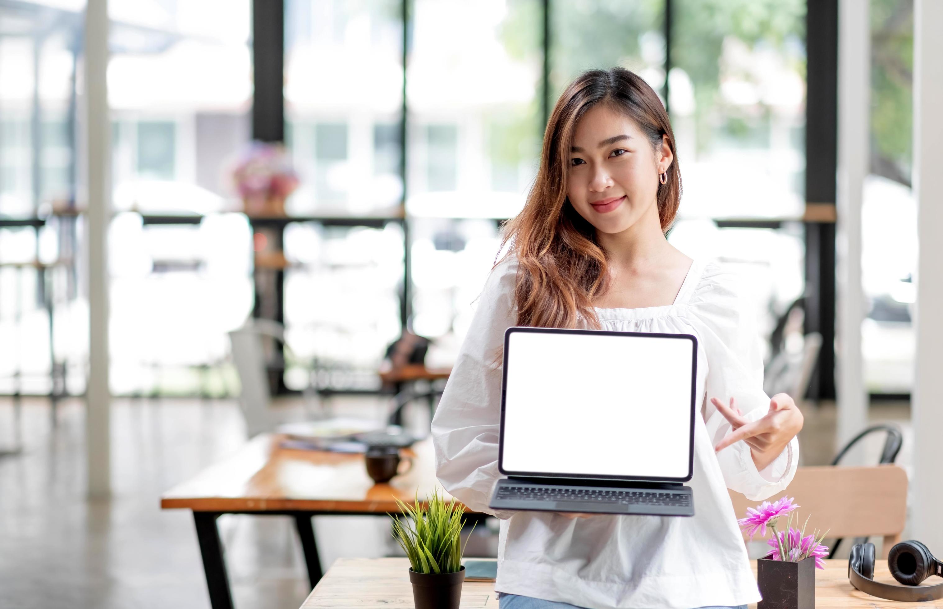 Happy young asian woman clothes on white background. People lifestyle concept. Mock up copy space. Hold laptop pc computer with blank empty screen Stock Free