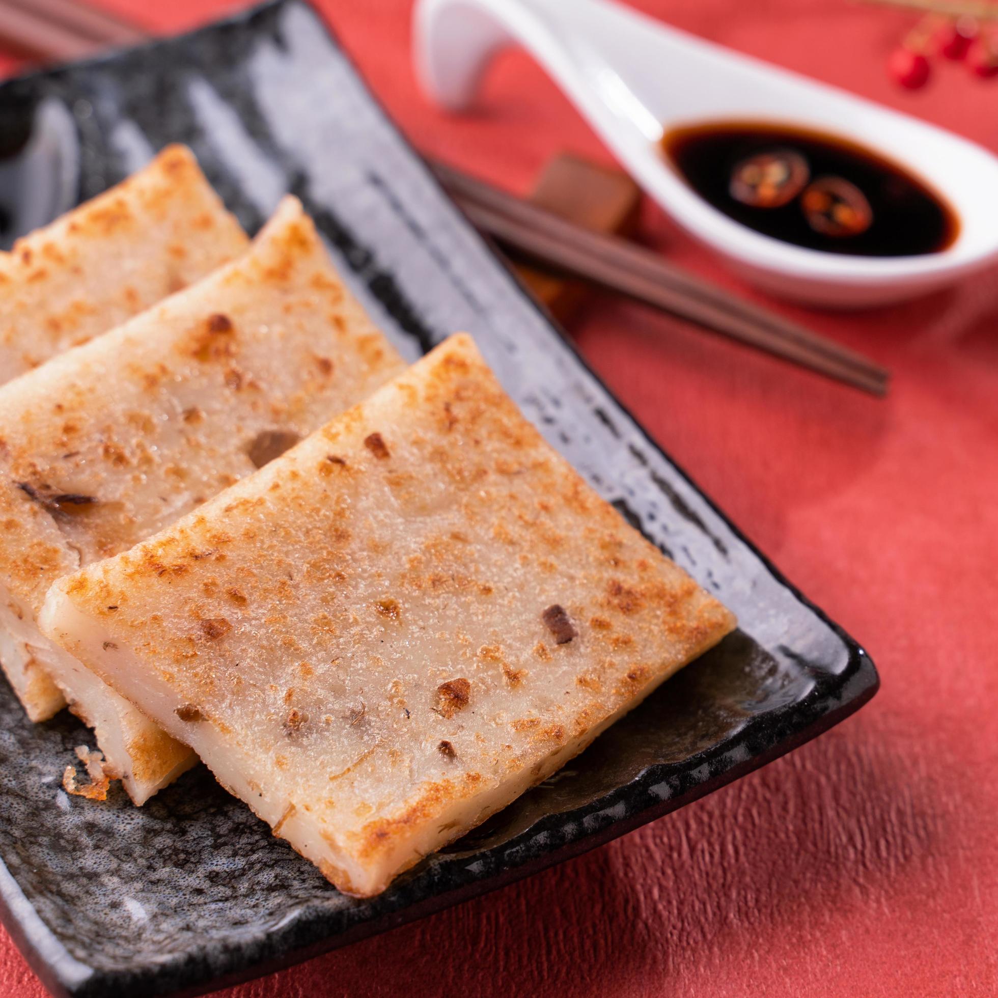 Chinese lunar new year food concept, Delicious turnip radish cake, local cuisine in restaurant with soy sauce on red background, close up, copy space Stock Free