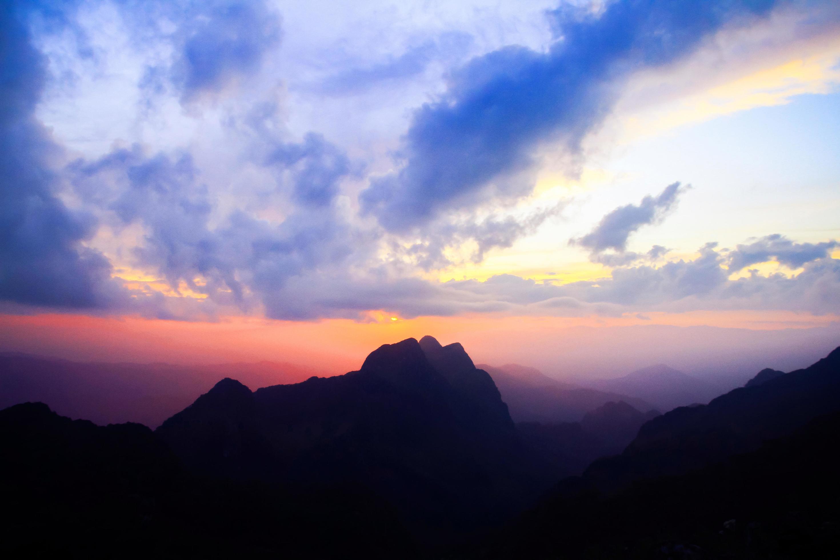 Sunset in sky and cloud, beautiful colorful twilight time with silhouette of mountain. Stock Free