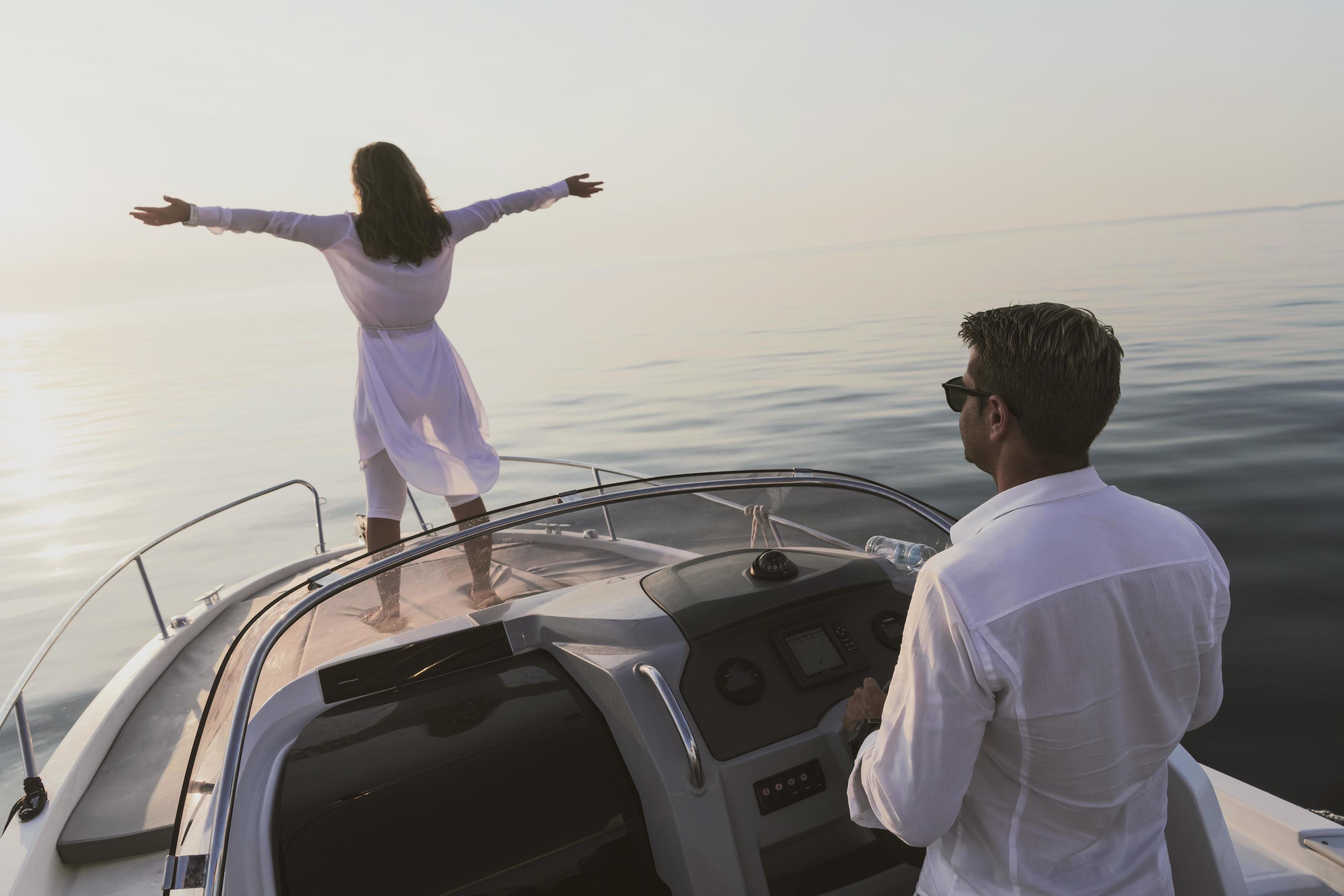 A senior couple in casual outfits with their son enjoy while riding a boat at sea at sunset. The concept of a happy family. Selective focus Stock Free