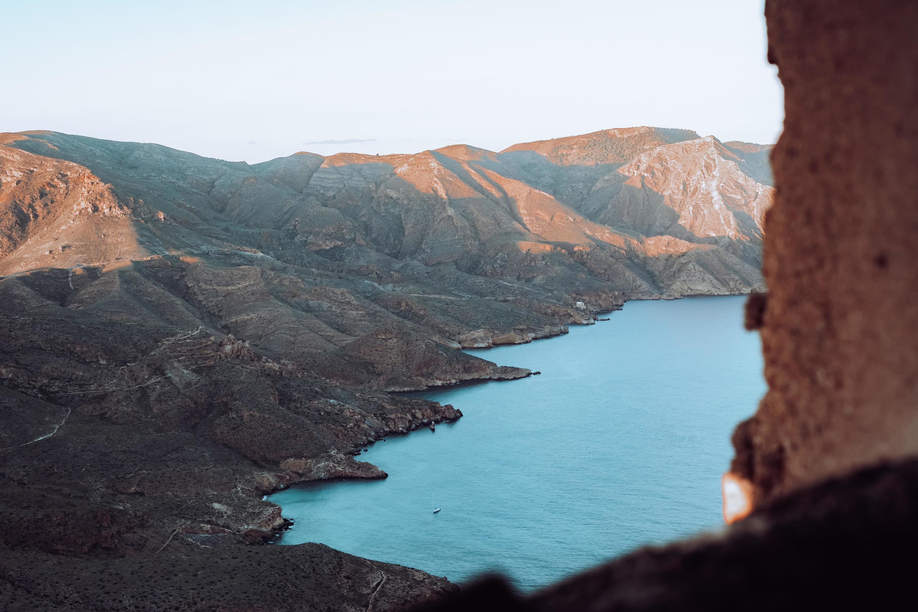 Brown and green mountains beside body of water during daytime Stock Free