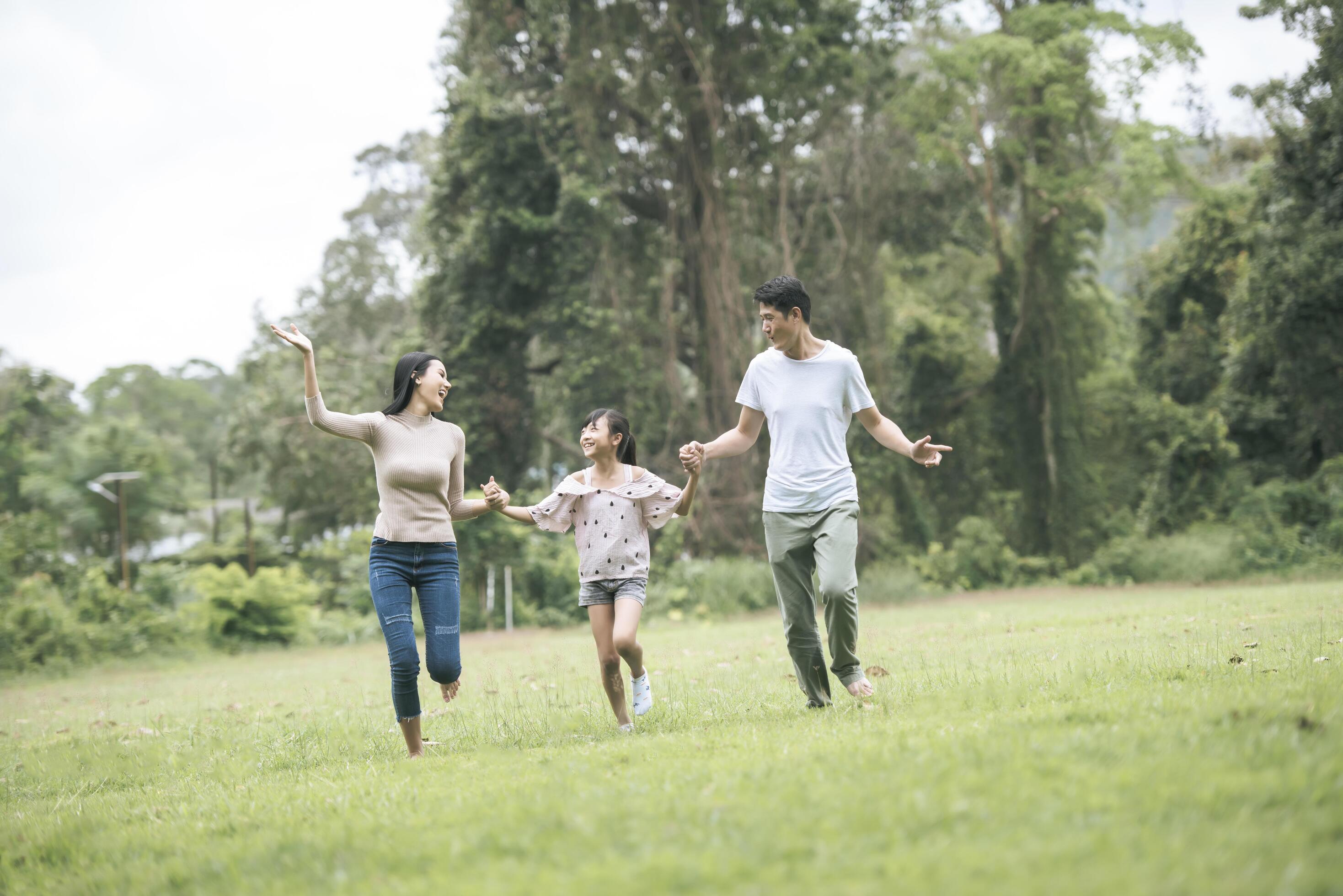 Happy family is having fun Mother, father and daughter are running in park. Stock Free