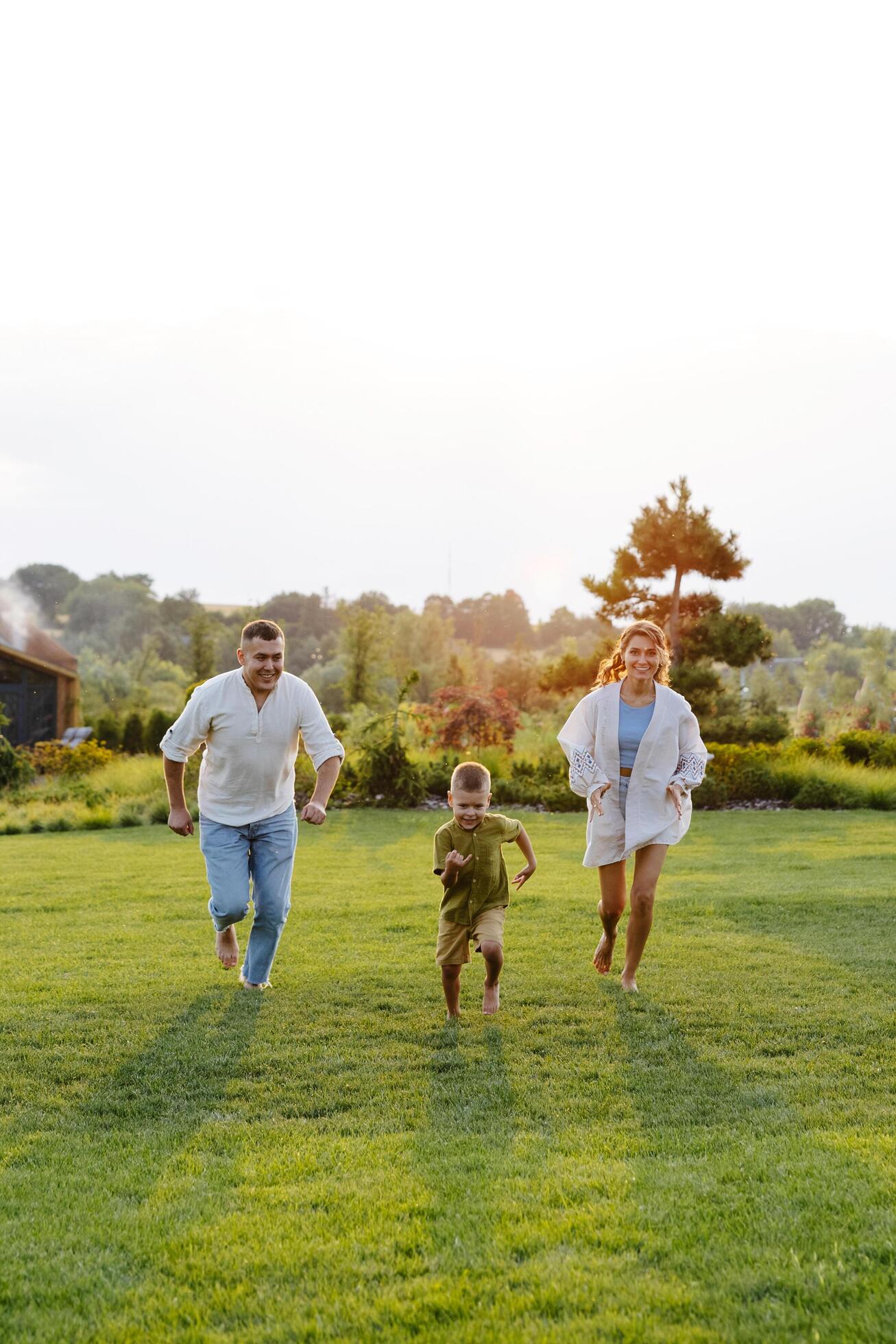 A Family Joyfully Running Across a Lush Green Grass Field on a Warm Summer Day, Basking in the Sunshine and Laughter Stock Free