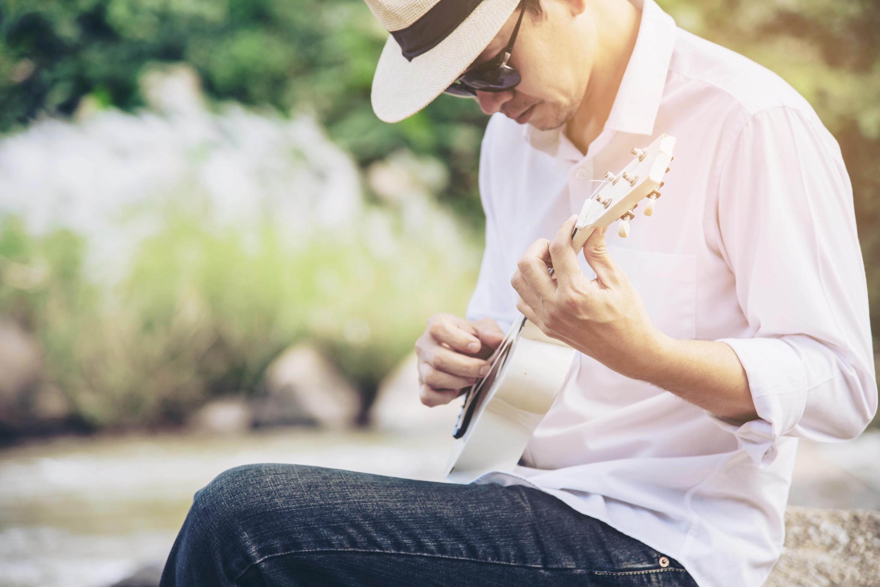 Man play ukulele new to the river- people and music instrument life style in nature concept Stock Free