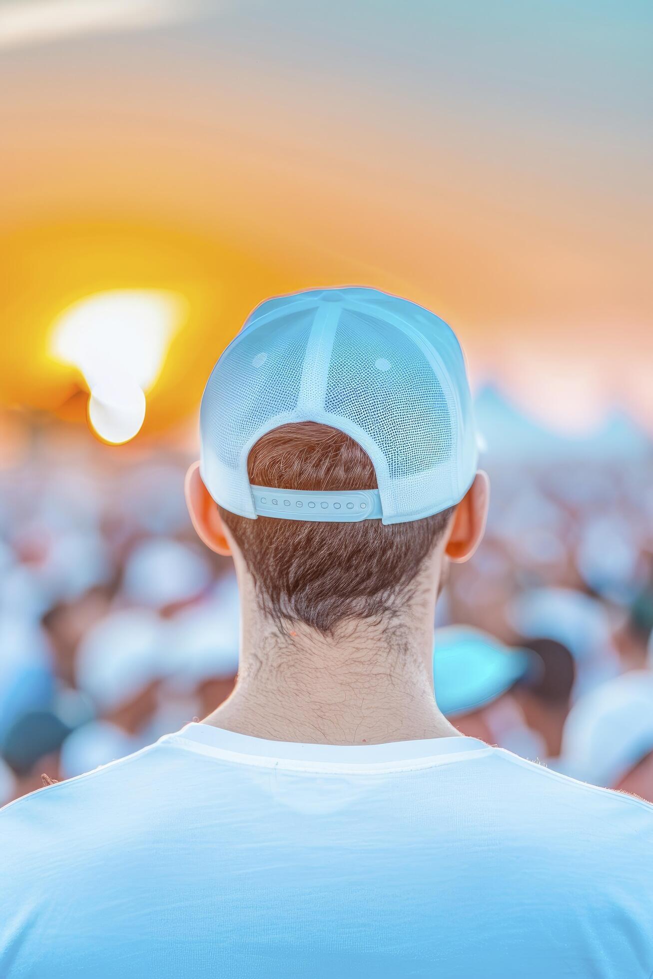 a man wearing cap and standing with crowd, many people infront of him in blur background during sunset Stock Free