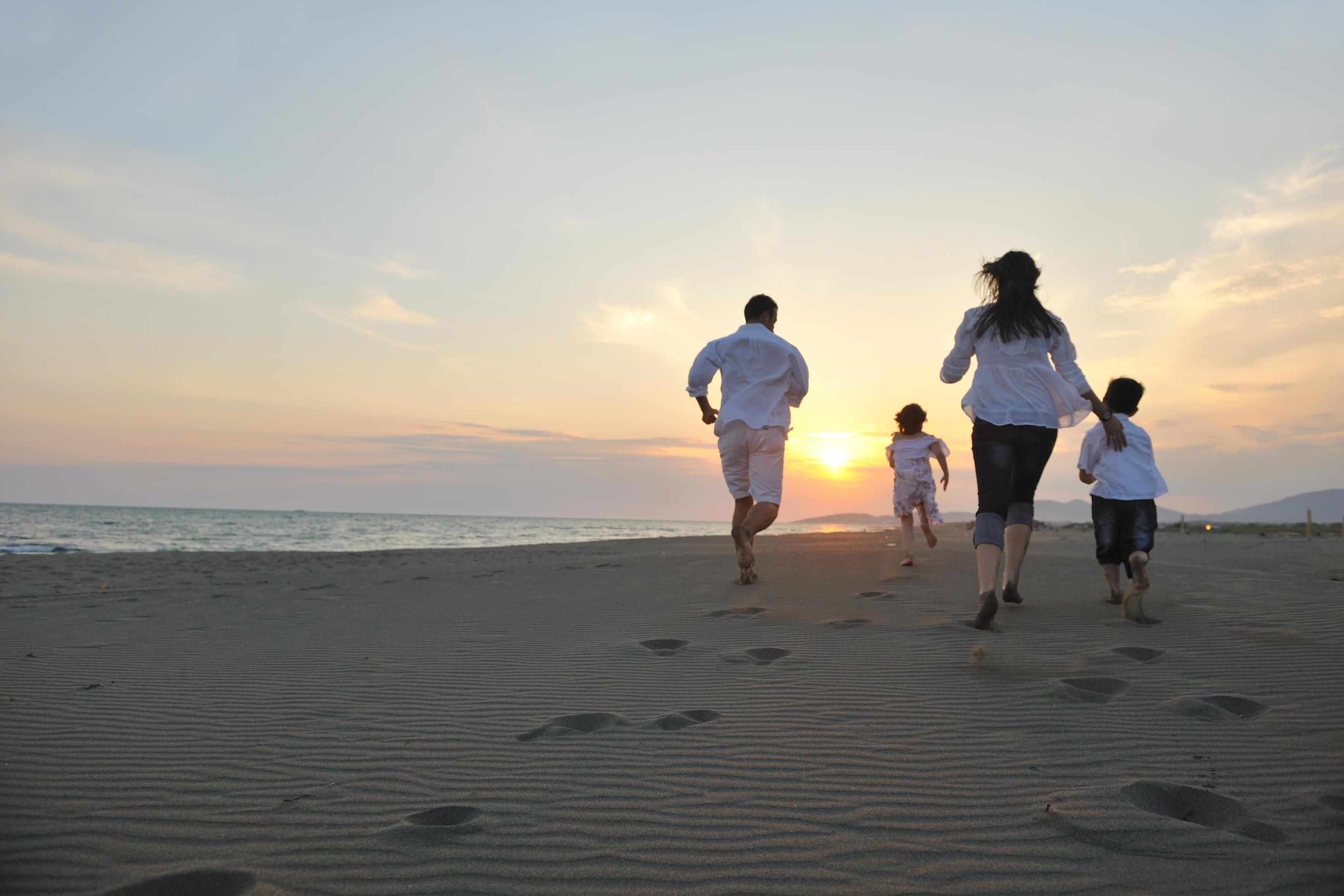 happy young family have fun on beach at sunset Stock Free