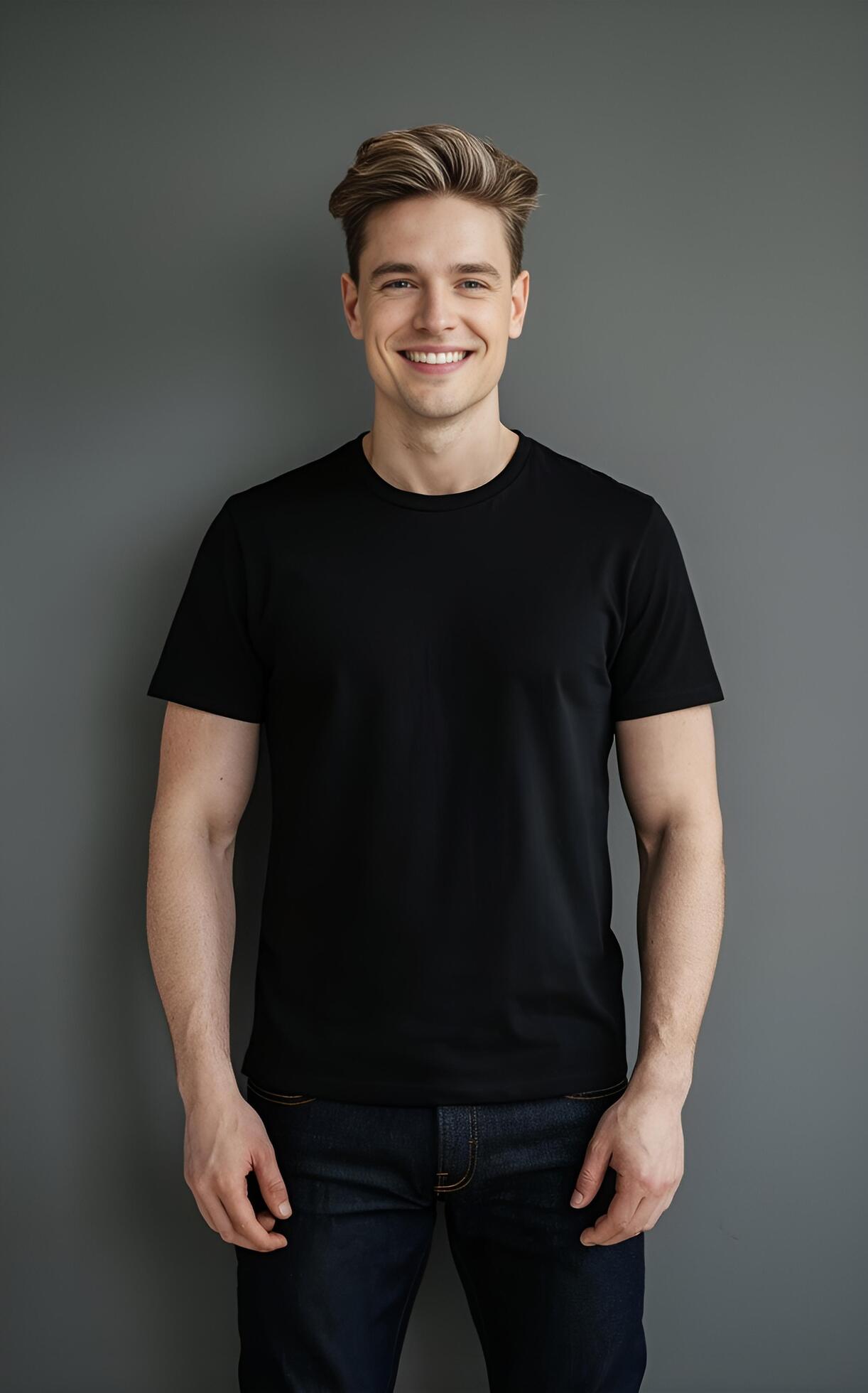 A portrait of a man in a black t-shirt and jeans, standing against a neutral grey background. Stock Free