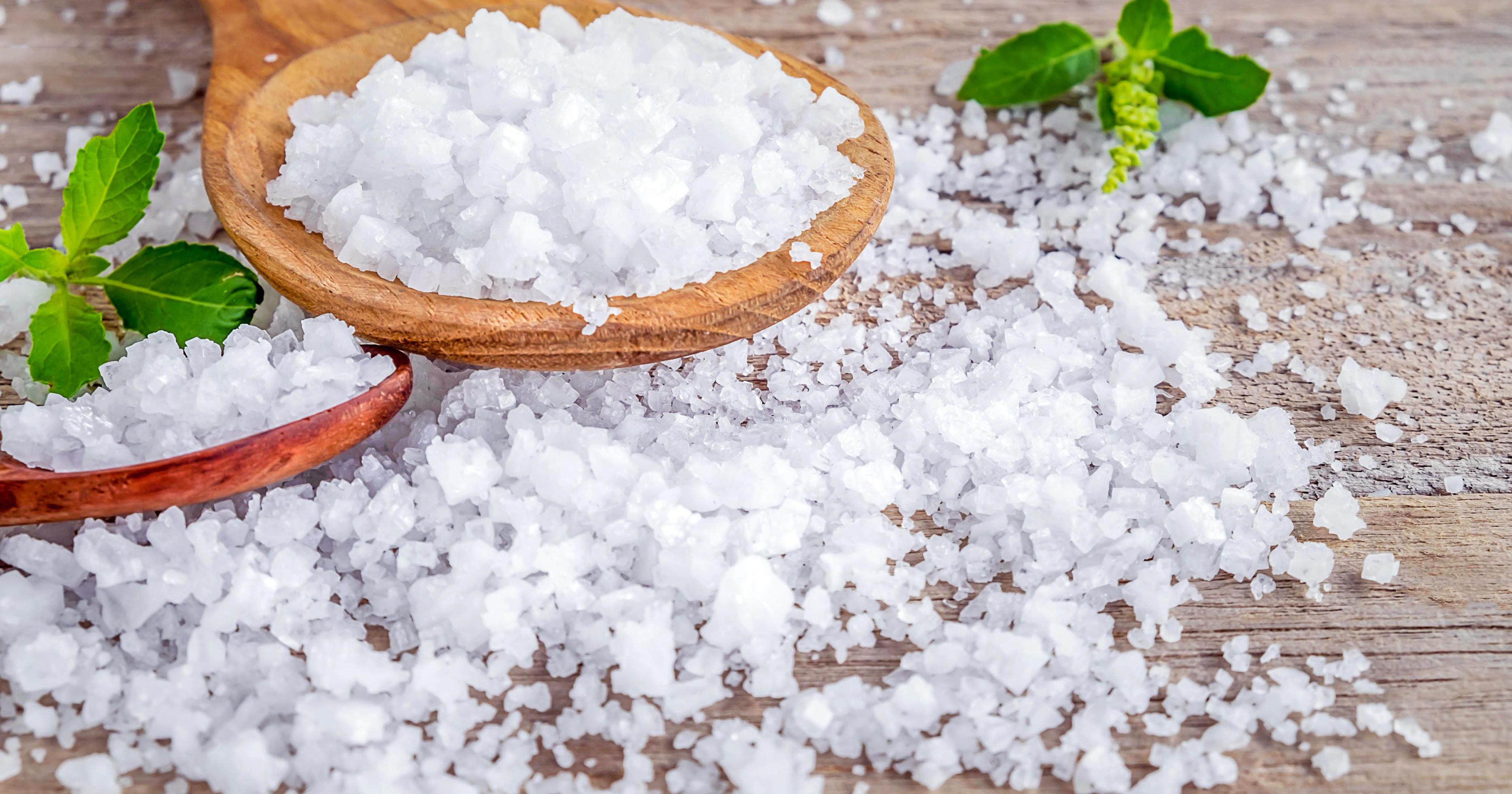 Close-up of salt crystals in wooden spoons on old wooden background.Salt flavored condiment salt.v Stock Free