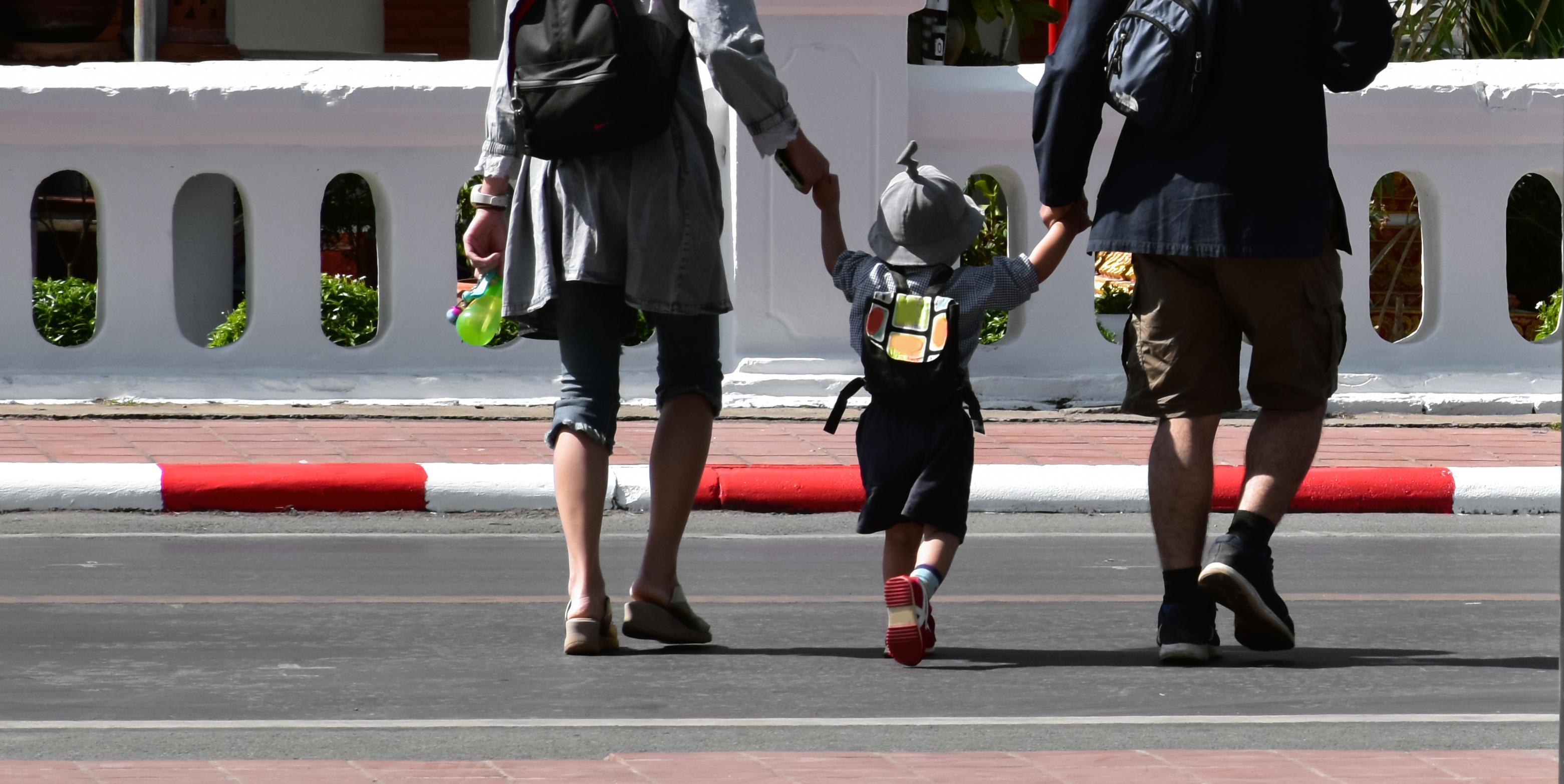 Asian parents family travellers hold thier son arms when they walked cross the street. Stock Free