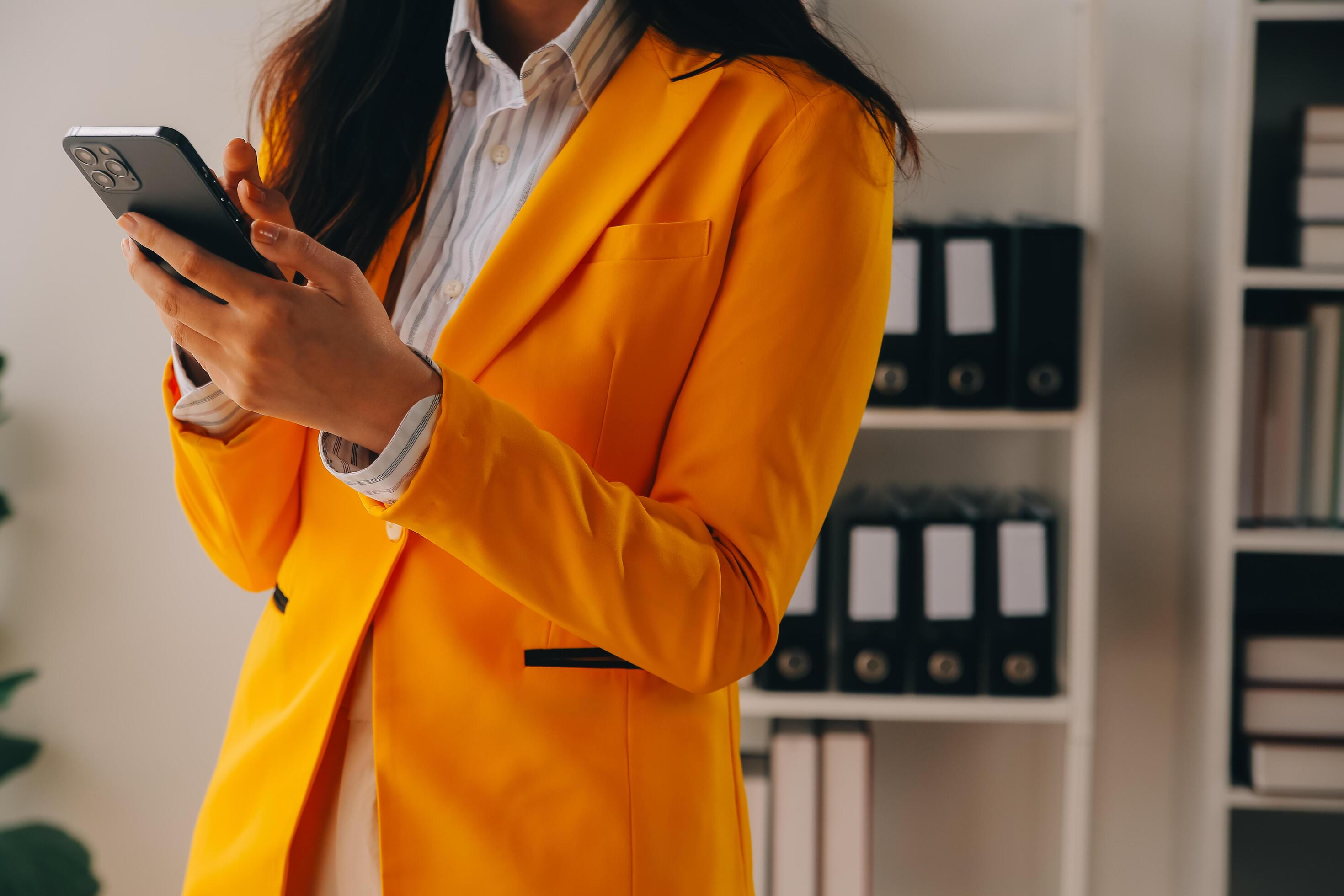 Young smiling business woman using smartphone near computer in office, copy space Stock Free