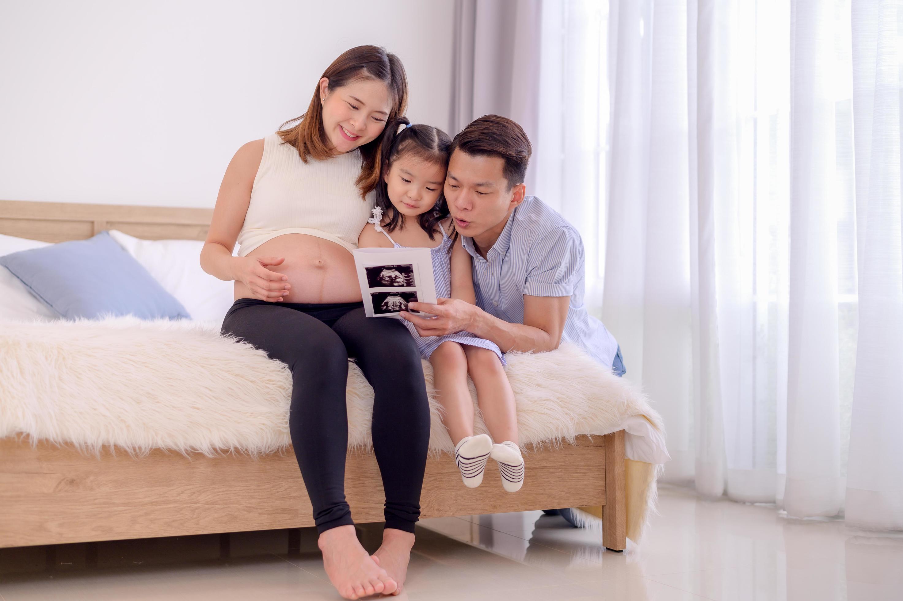 An Asian family, parents and daughters are watching an ultrasound film of a child in their mother’s womb Stock Free