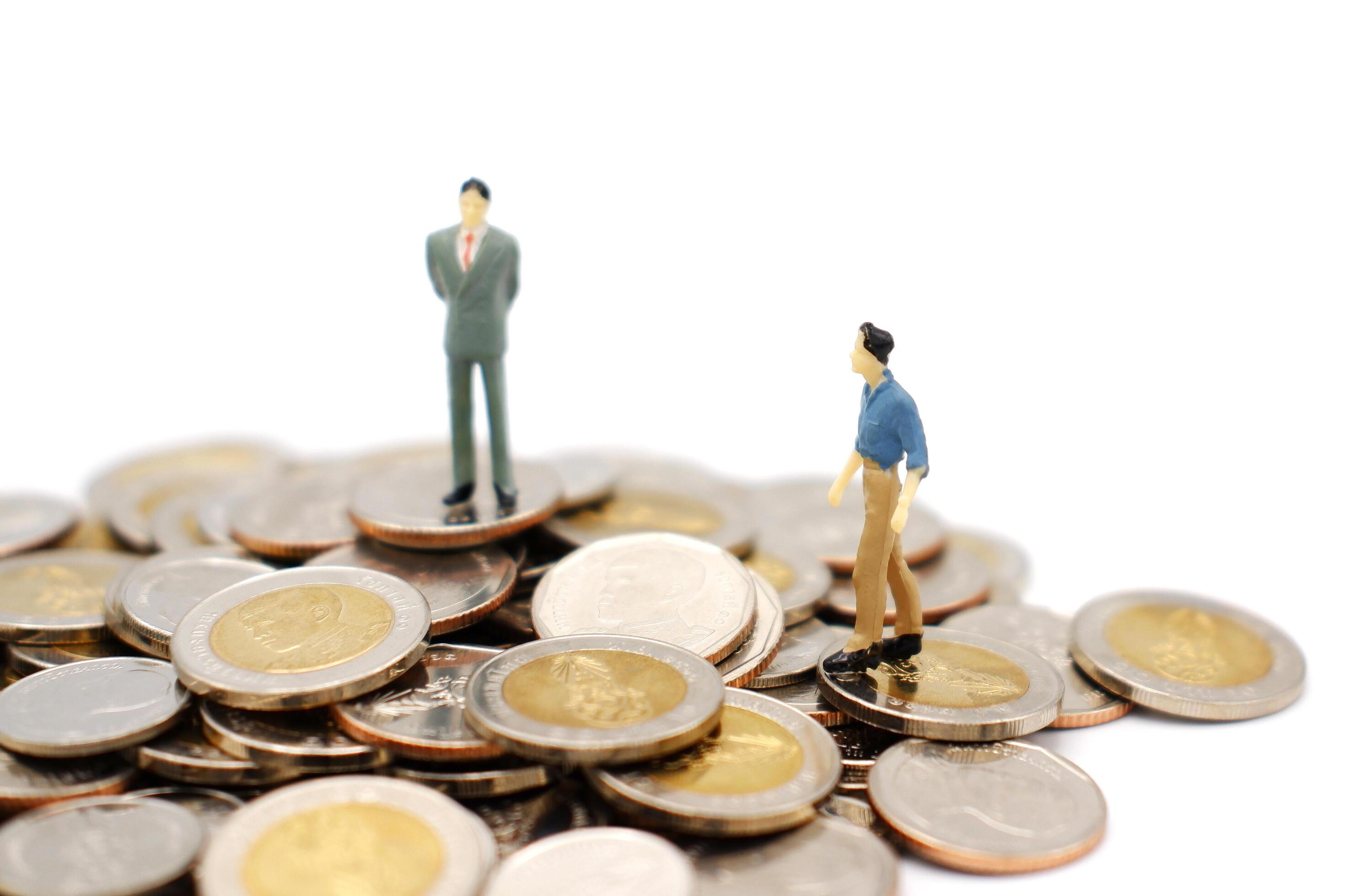 Two miniature people walking and standing on pile of new Thai Baht coins, isolated on white background. Business and finance concept. Stock Free