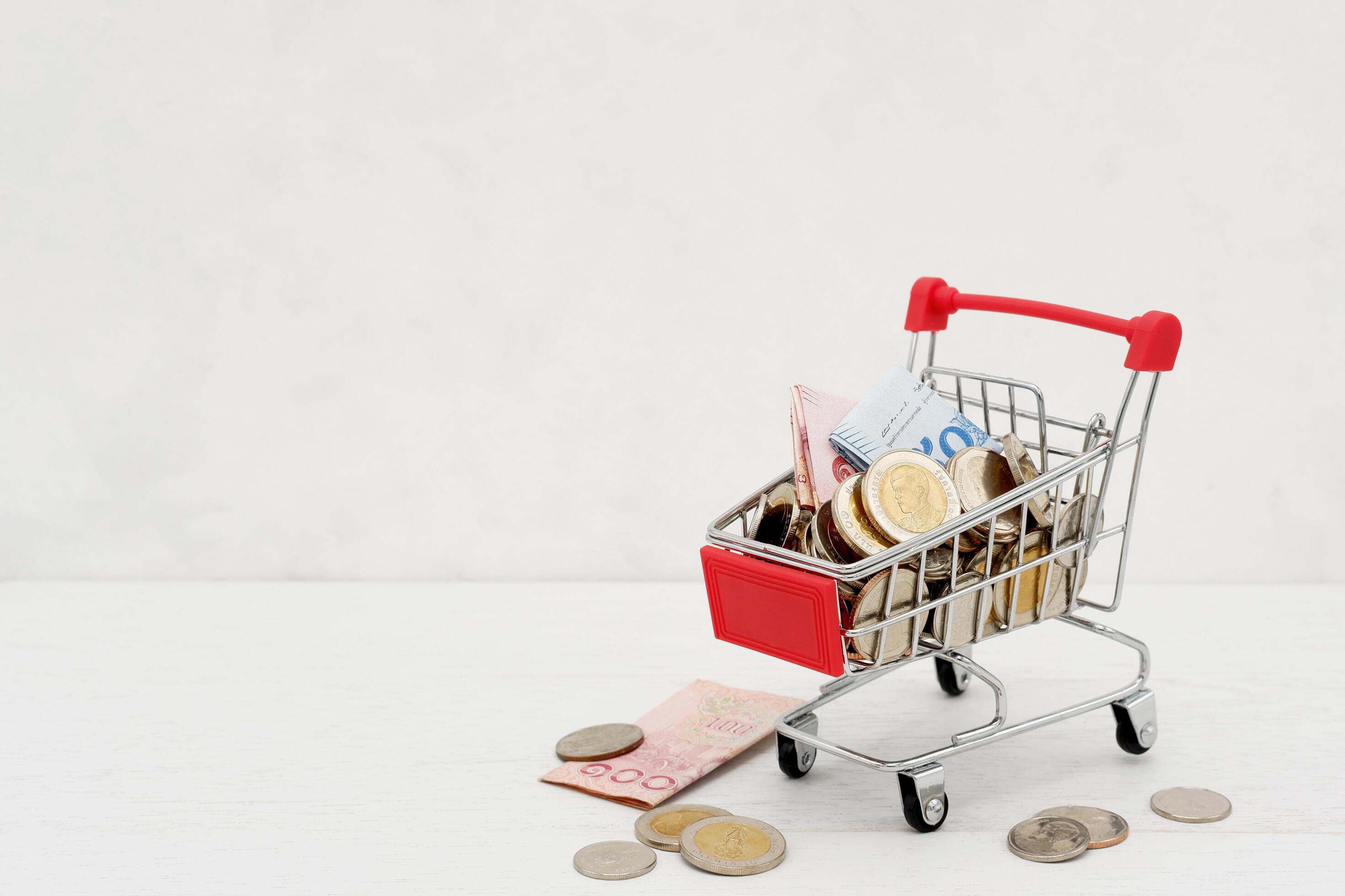 New Thai Baht banknotes and coins in red miniature shopping cart. Business and finance concept. Stock Free