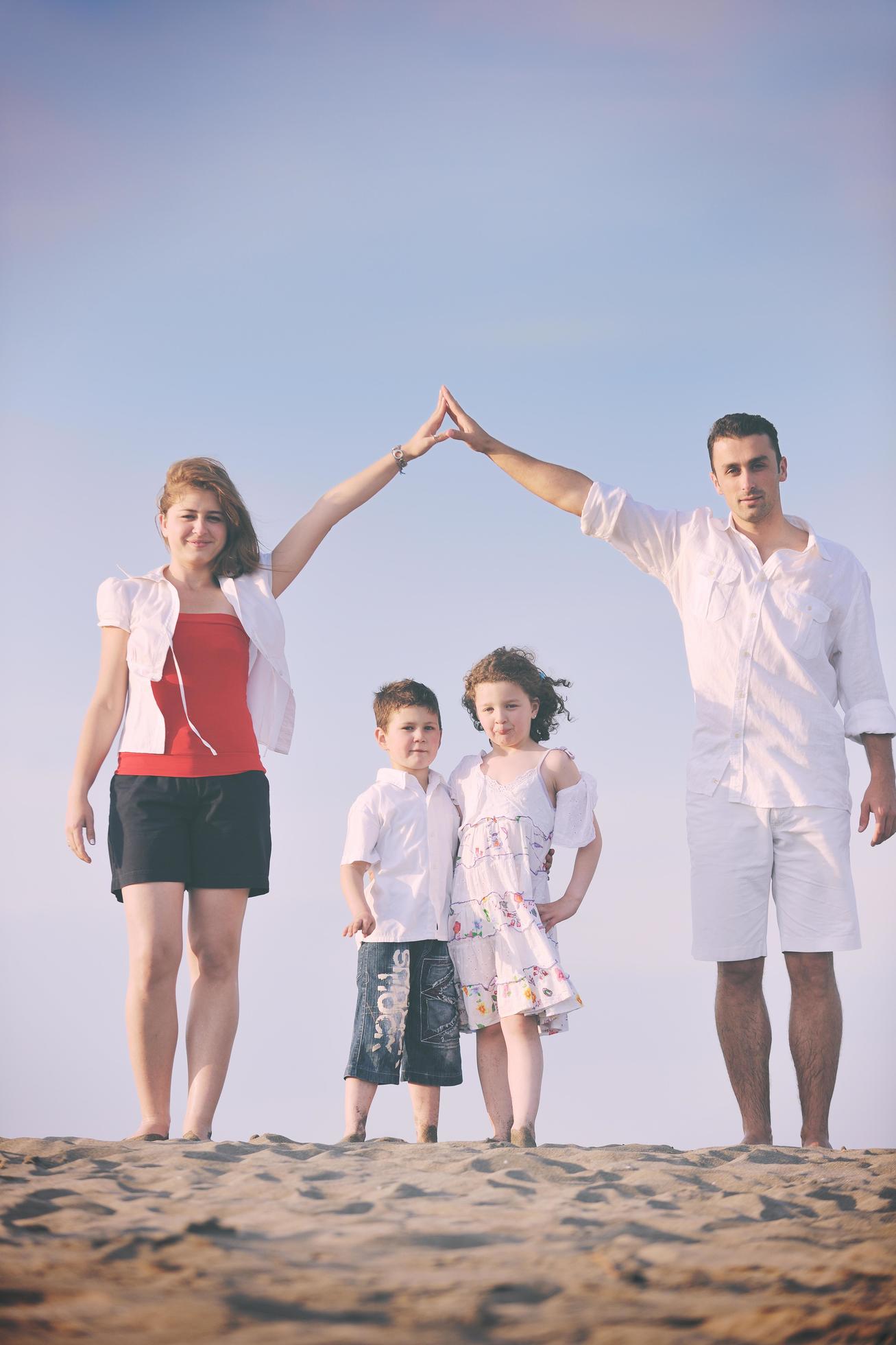 family on beach showing home sign Stock Free