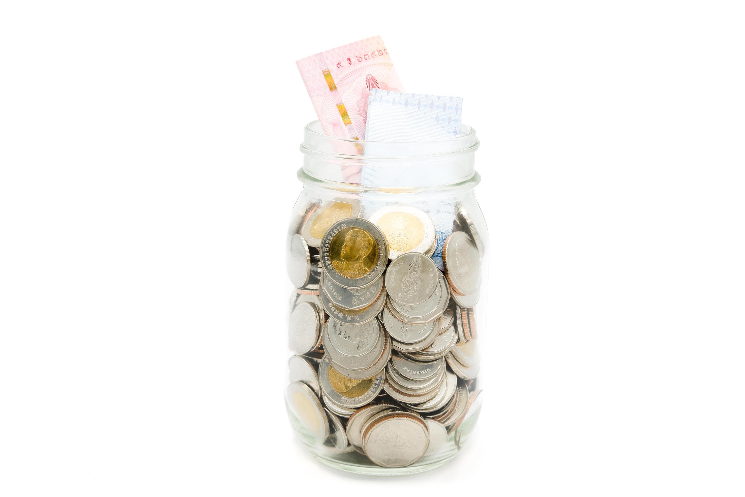 Thai Baht banknotes and coins in a glass jar. Business and finance concept. Stock Free