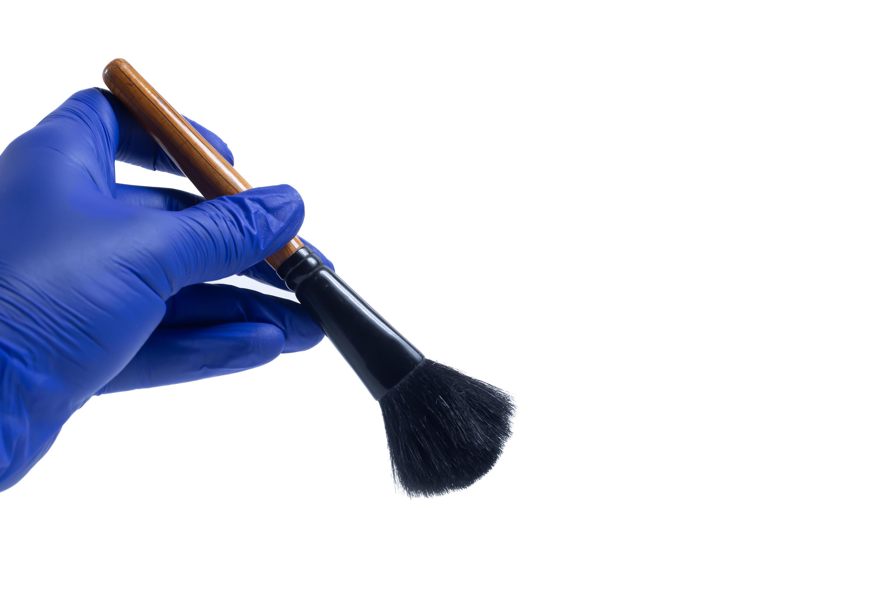 
									Hand in blue glove holding a makeup brush isolated on white background. Stock Free