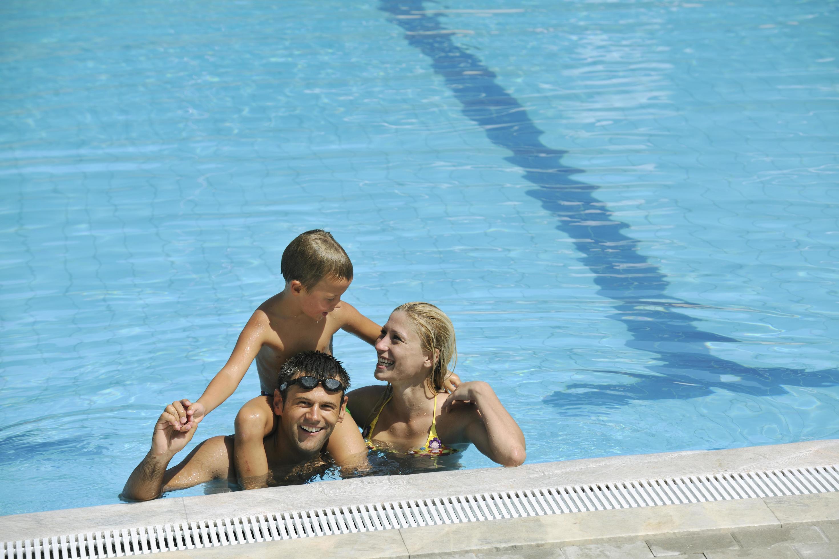 happy young family have fun on swimming pool Stock Free