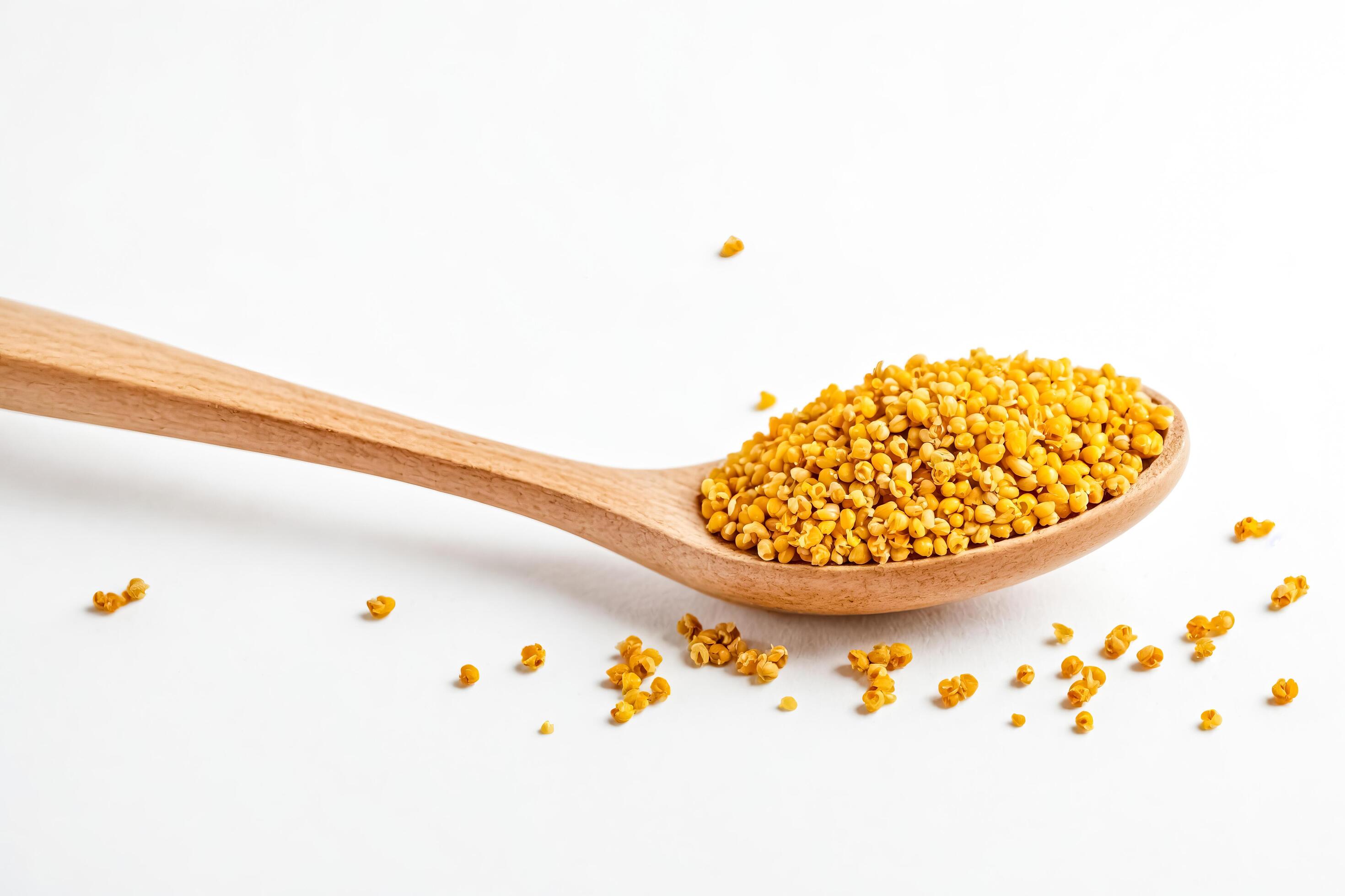 Golden Millet Seeds in a Wooden Spoon on a White Background Stock Free