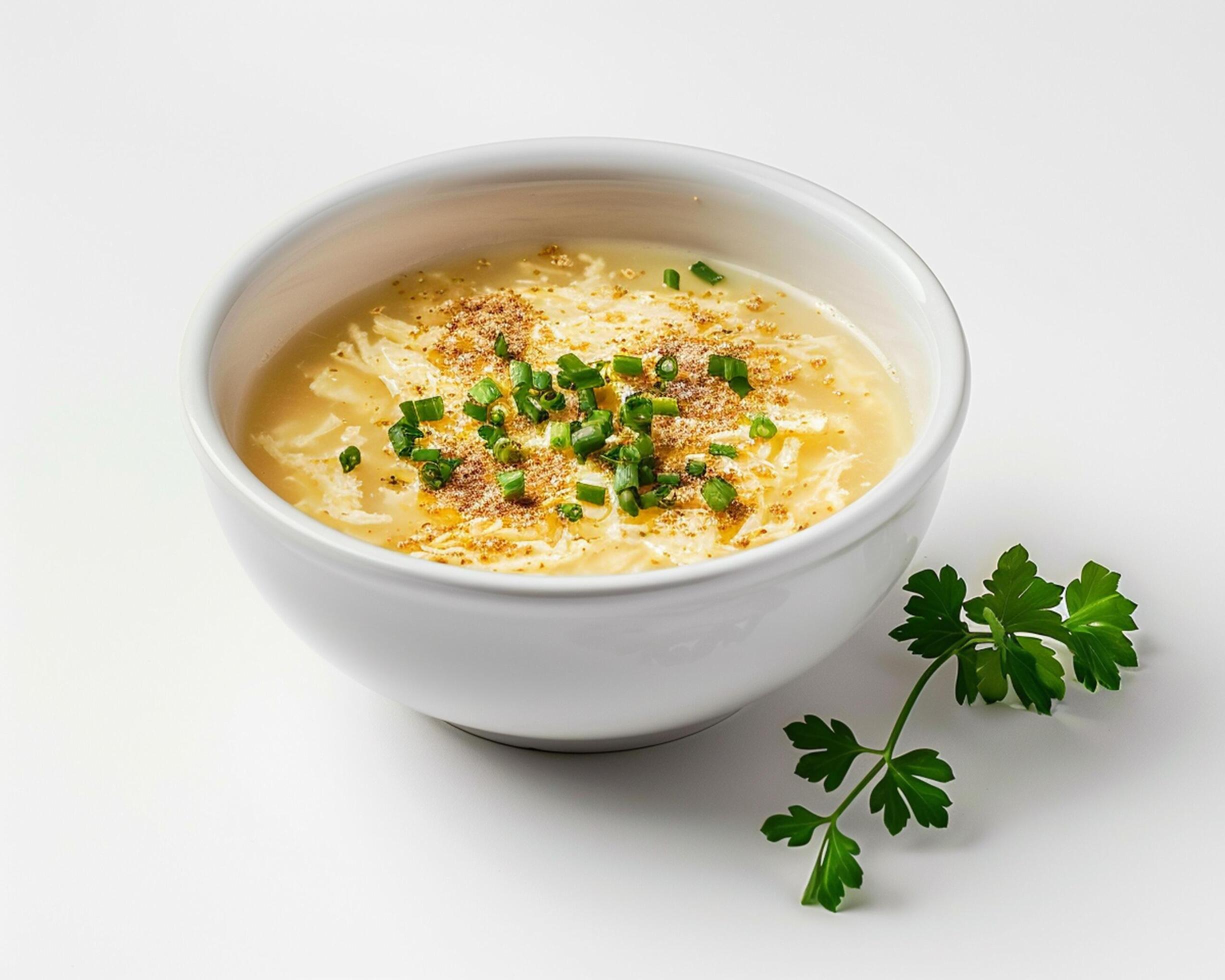 a bowl of soup with cheese and herbs on a white background Stock Free