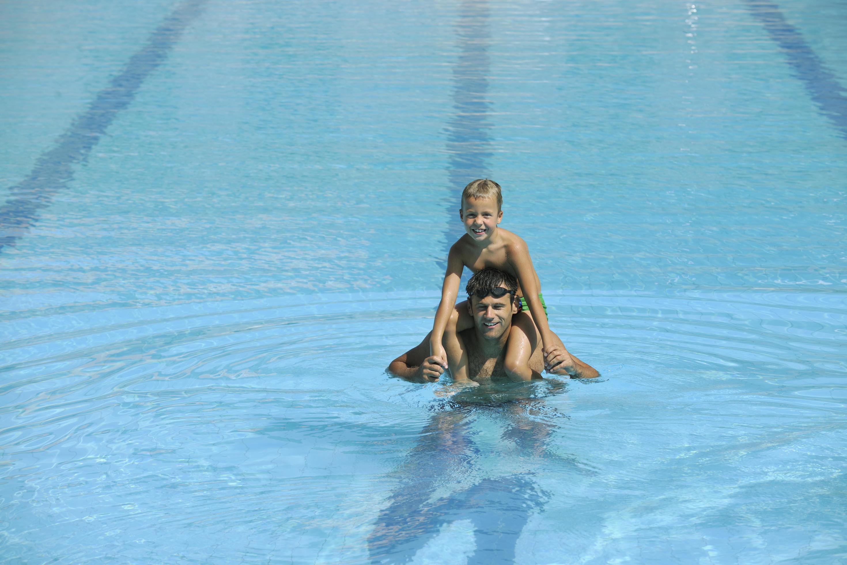 happy young family have fun on swimming pool Stock Free