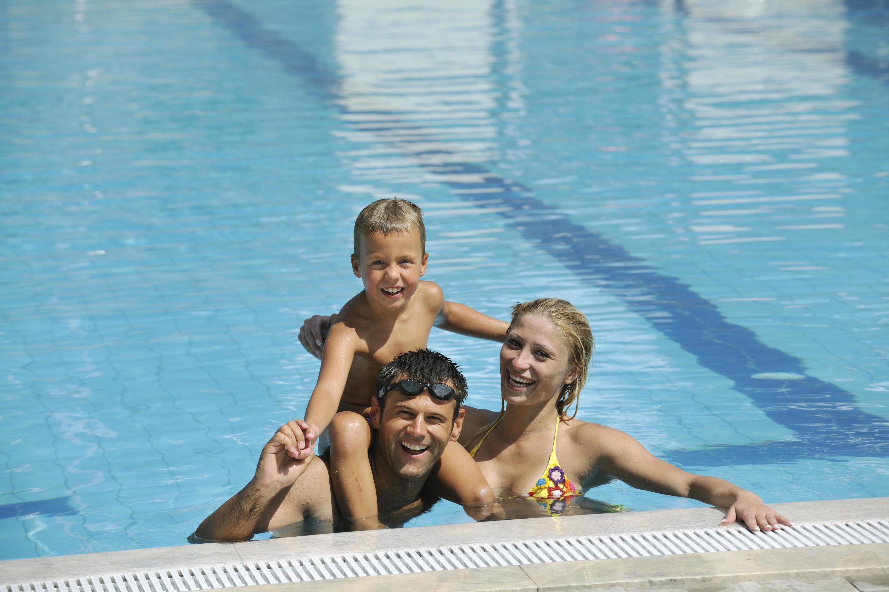 happy young family have fun on swimming pool Stock Free