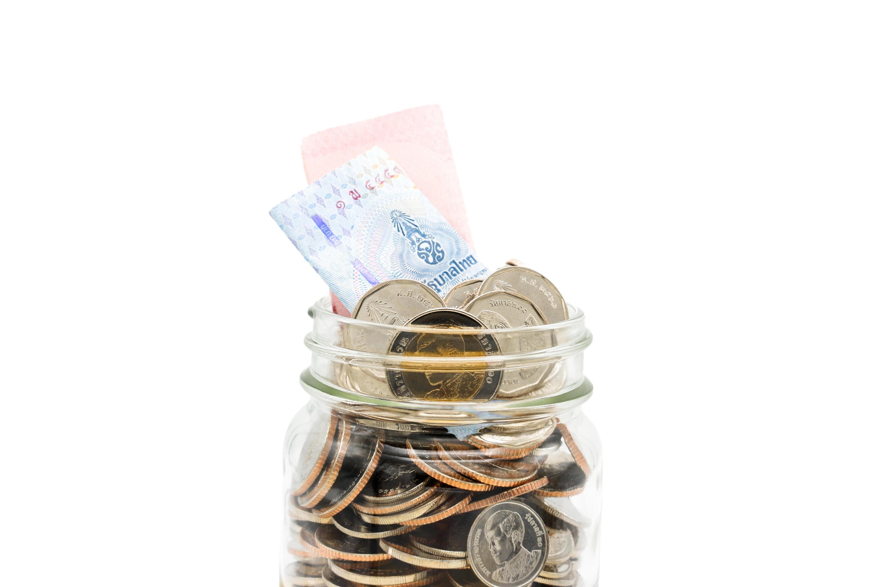 Thai Baht banknotes and coins in a glass jar. Business and finance concept. Stock Free