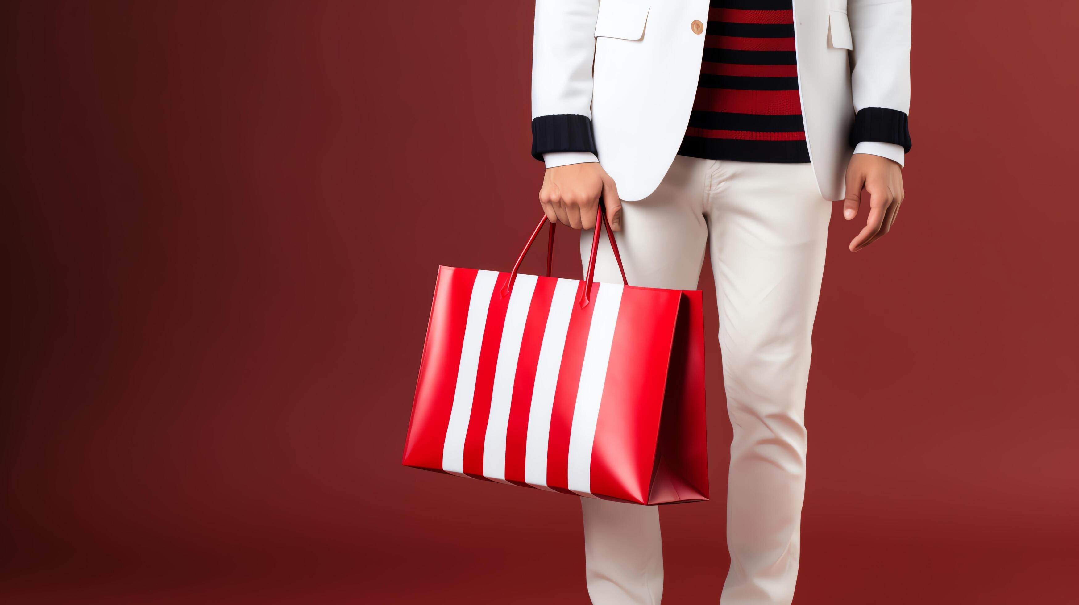 A model wearing a white suit and striped shirt holds a red and white striped tote bag. Stock Free