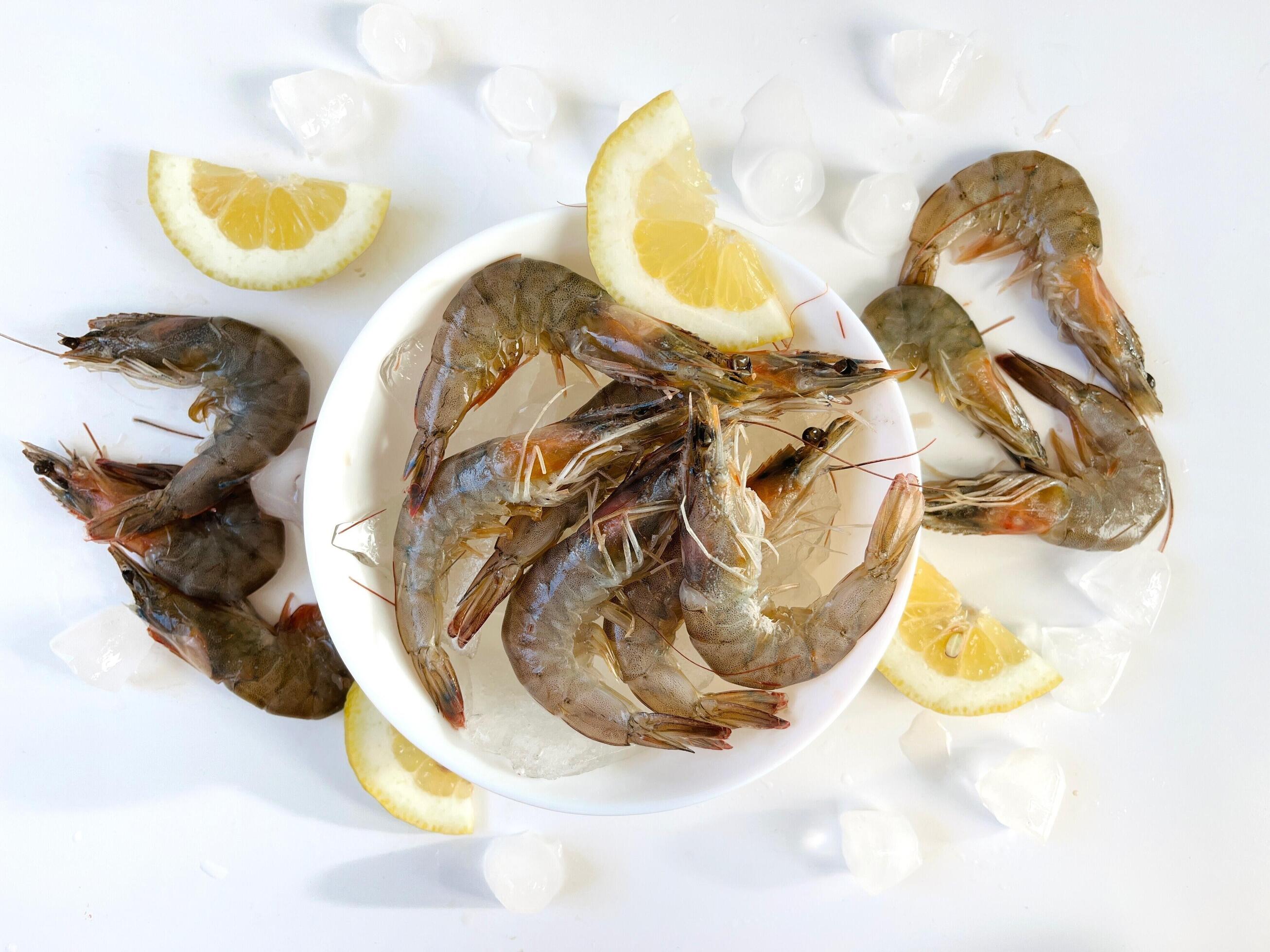 Healthy food. Fresh shrimps with ice and lemon on plate on white background top view Stock Free