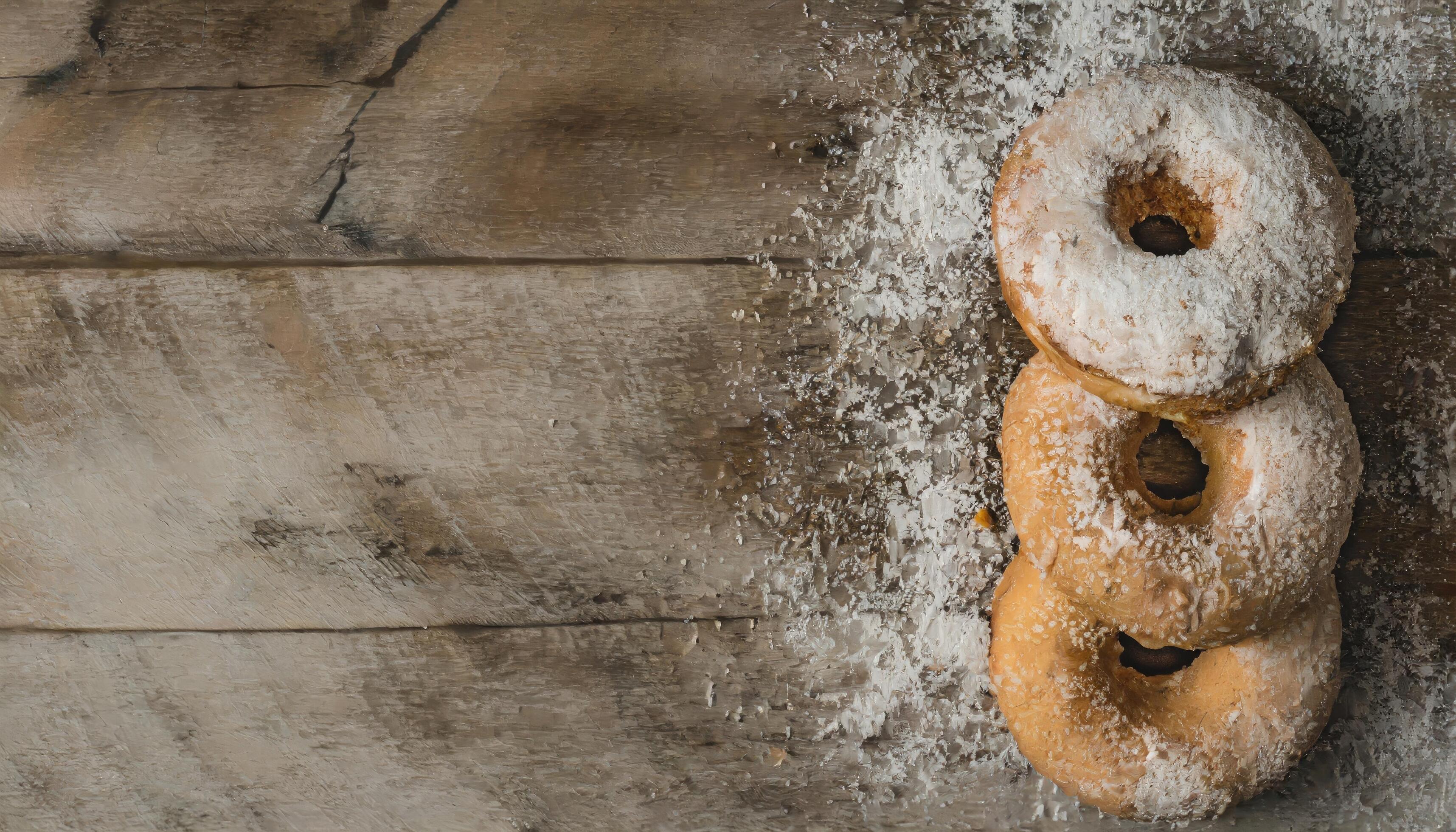 Copy Space image of Donuts with powdered sugar on wooden table on black background Stock Free