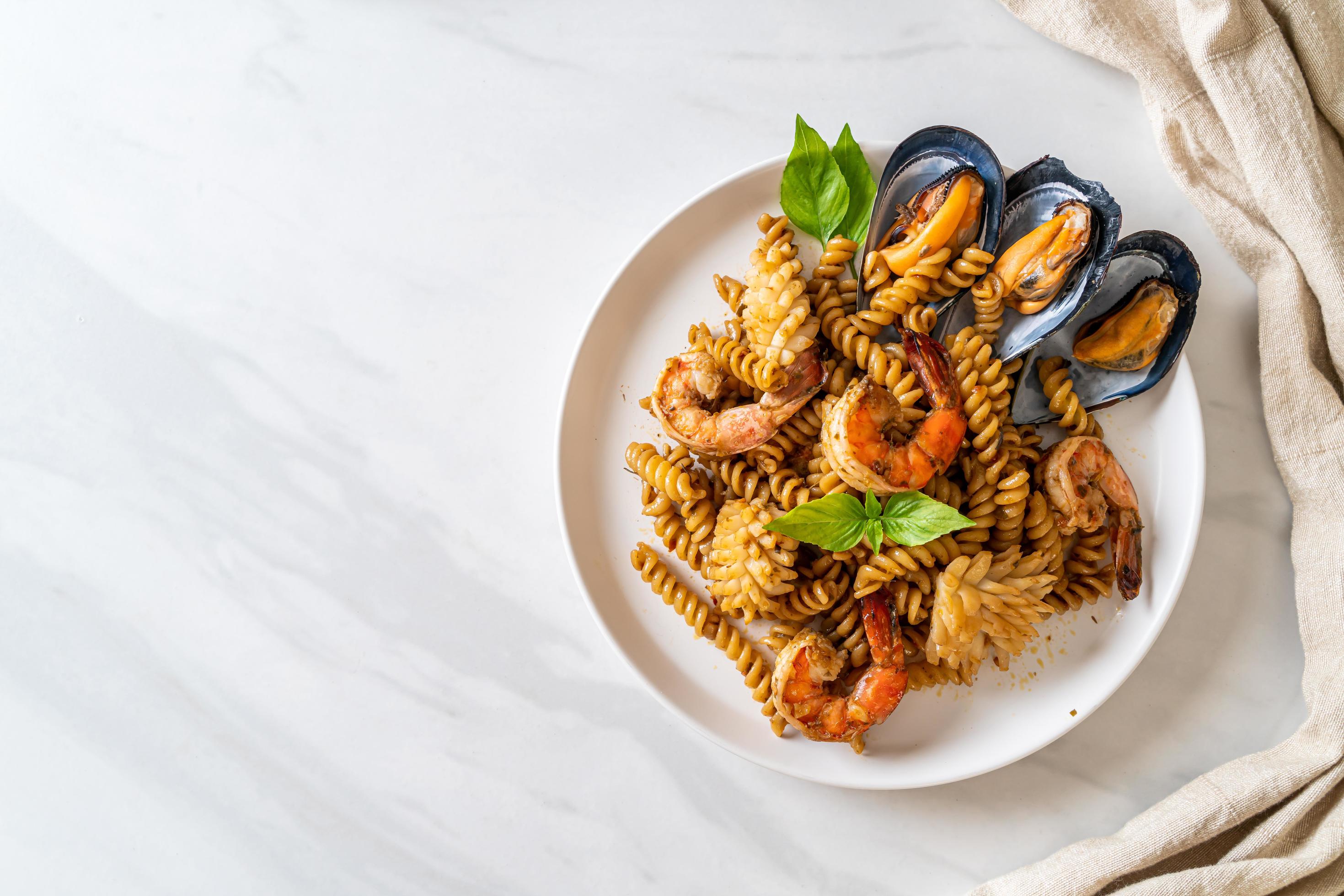 Stir-fried spiral pasta with seafood and basil sauce – fusion food style Stock Free