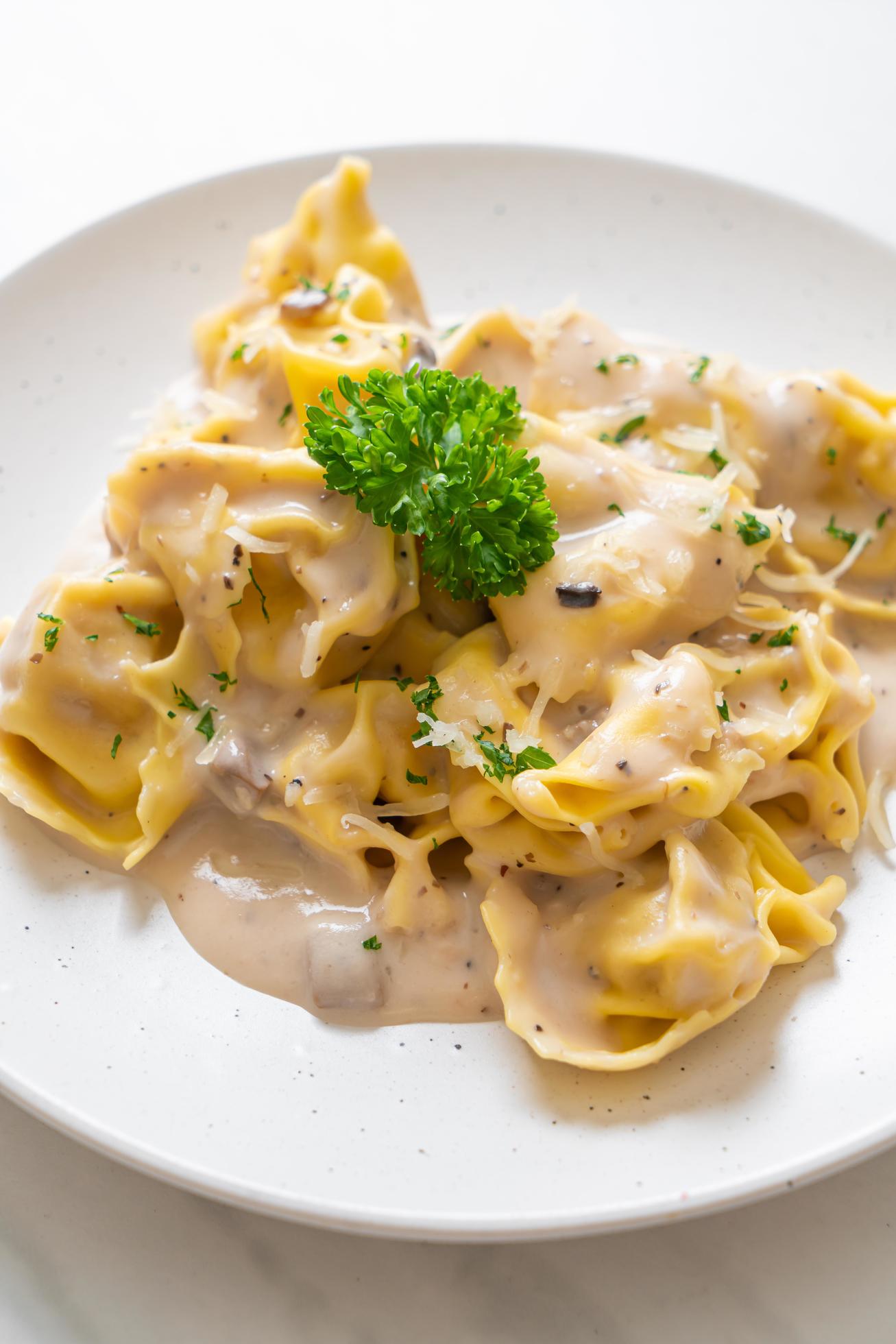 Tortellini pasta with mushroom cream sauce and cheese – Italian food style Stock Free