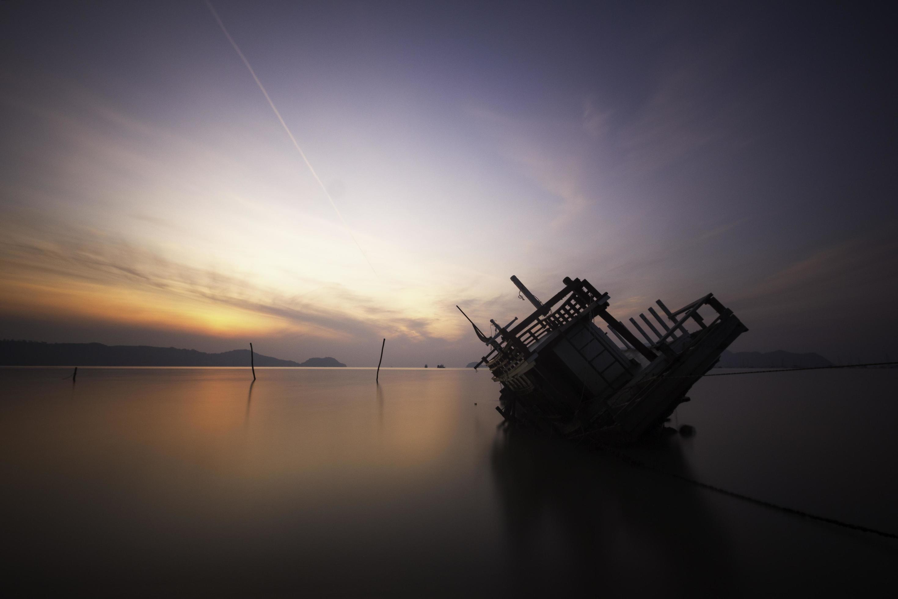 
									Sinking boat in the sea during sunrise Stock Free