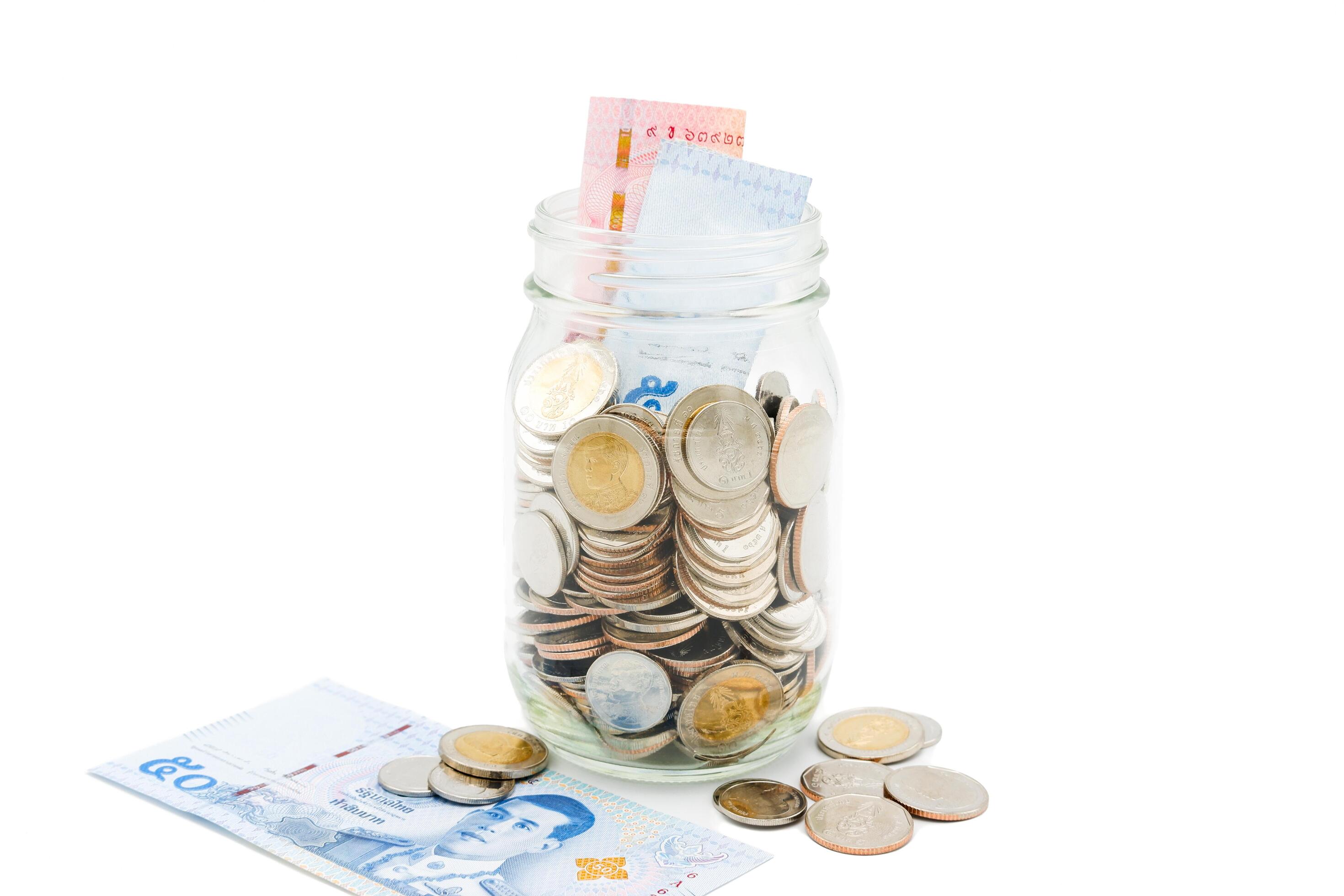 Thai Baht banknotes and coins in a glass jar. Business and finance concept. Stock Free