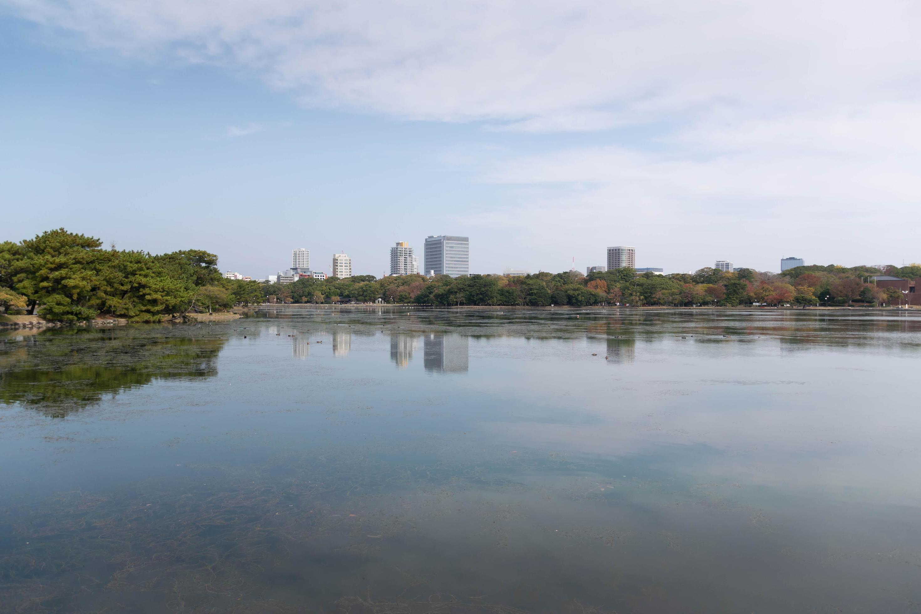 view of city town skyline over the pond lake natural view under daytime in japan, big city with natural lake public Stock Free