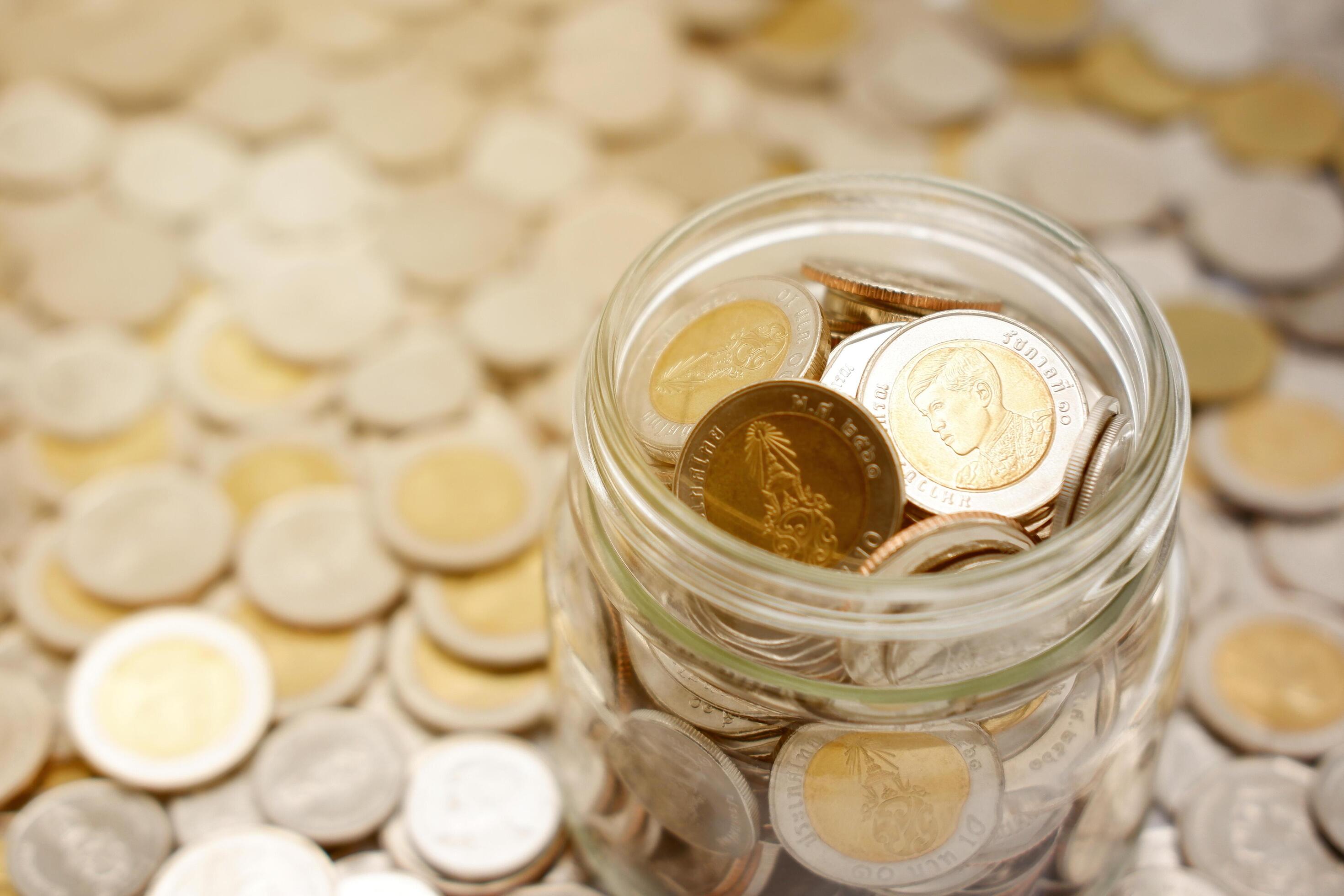 Close-up image of a glass jar full of new Thai baht coins. Business and finance concept. Stock Free