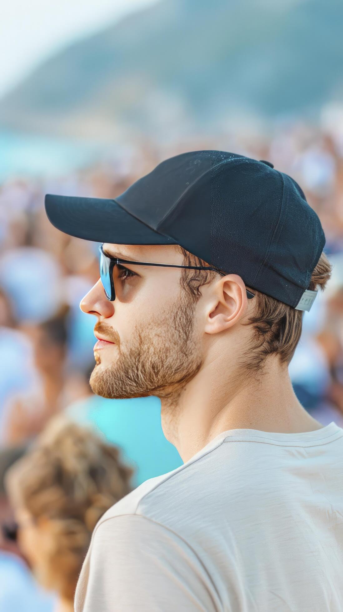 a man wearing cap and standing with crowd, many people infront of him in blur background during sunset Stock Free