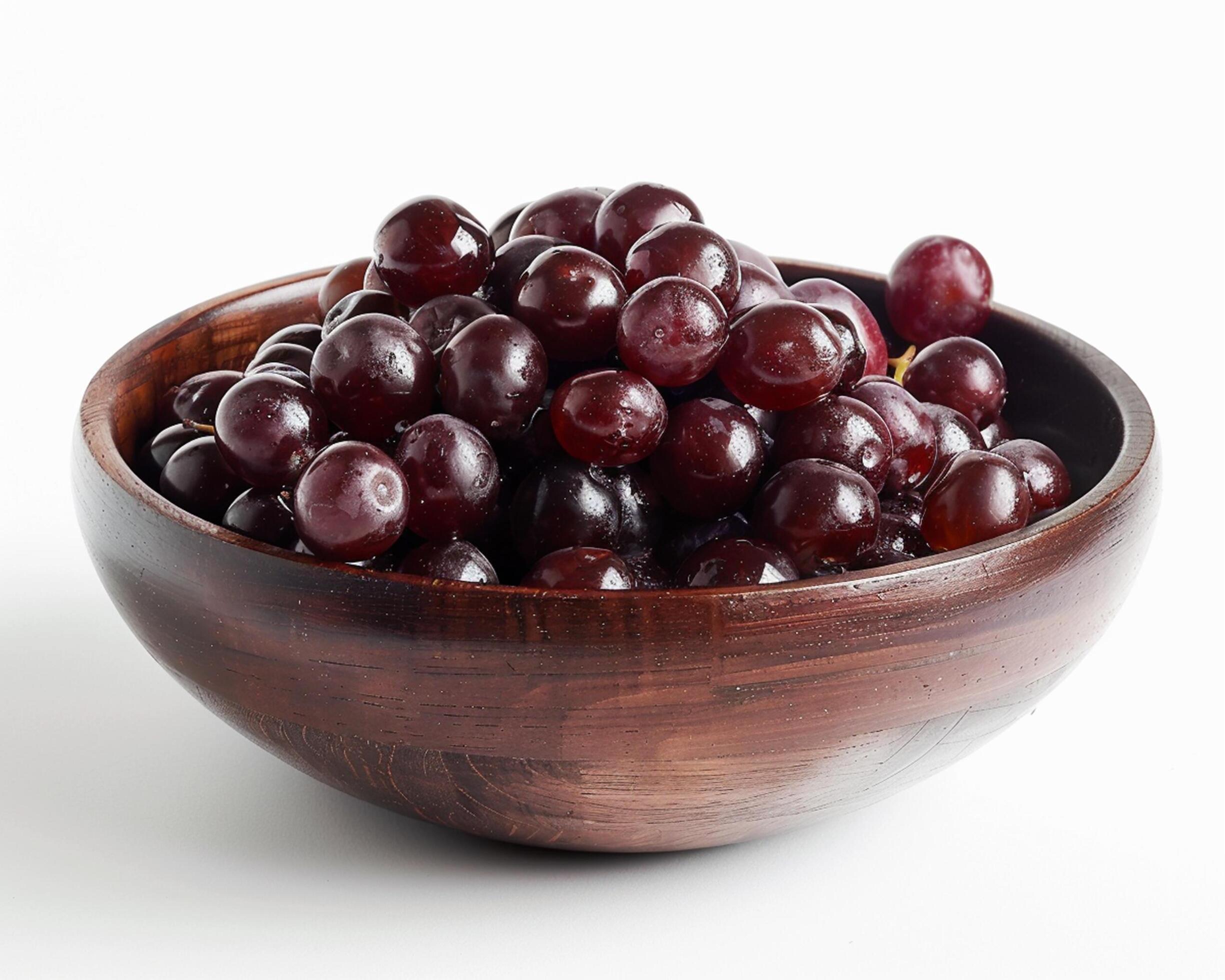 a wooden bowl filled with grapes Stock Free