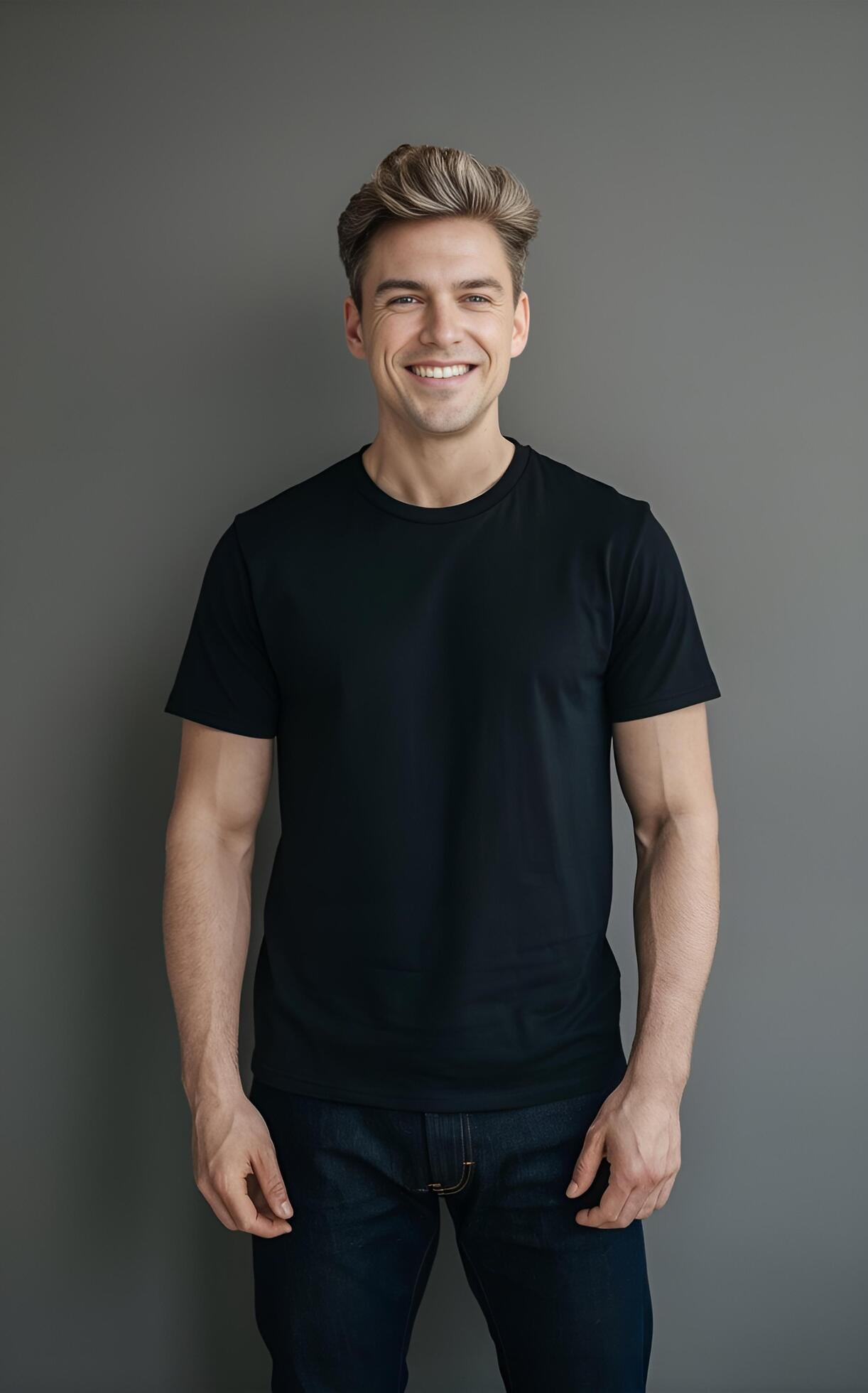 A portrait of a man in a black t-shirt and jeans, standing against a neutral grey background. Stock Free