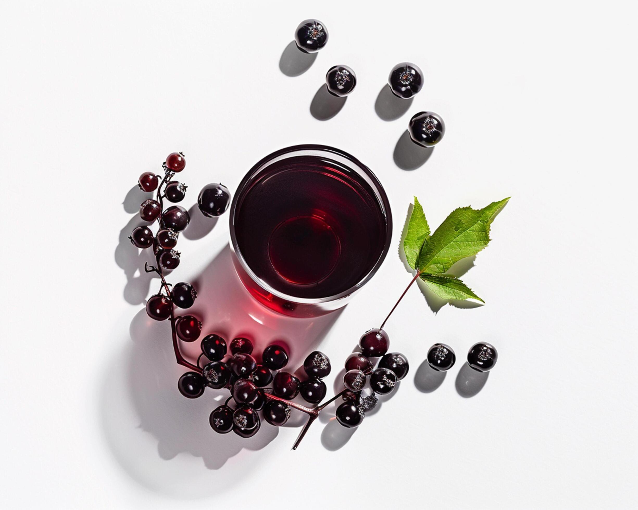 a glass of black currant with berries on a white surface Stock Free