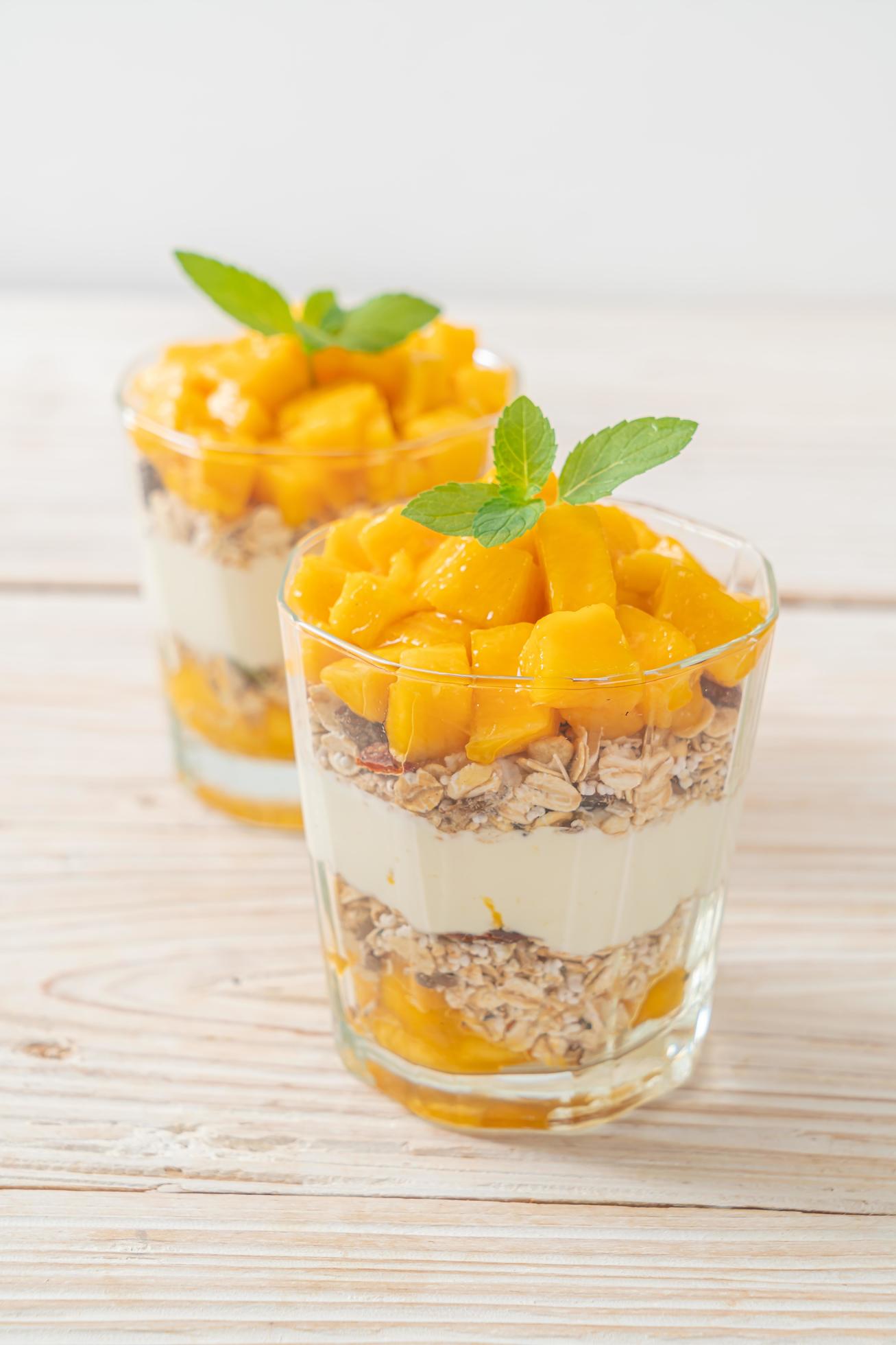 Fresh mango yogurt with granola in glass – healthy food style Stock Free