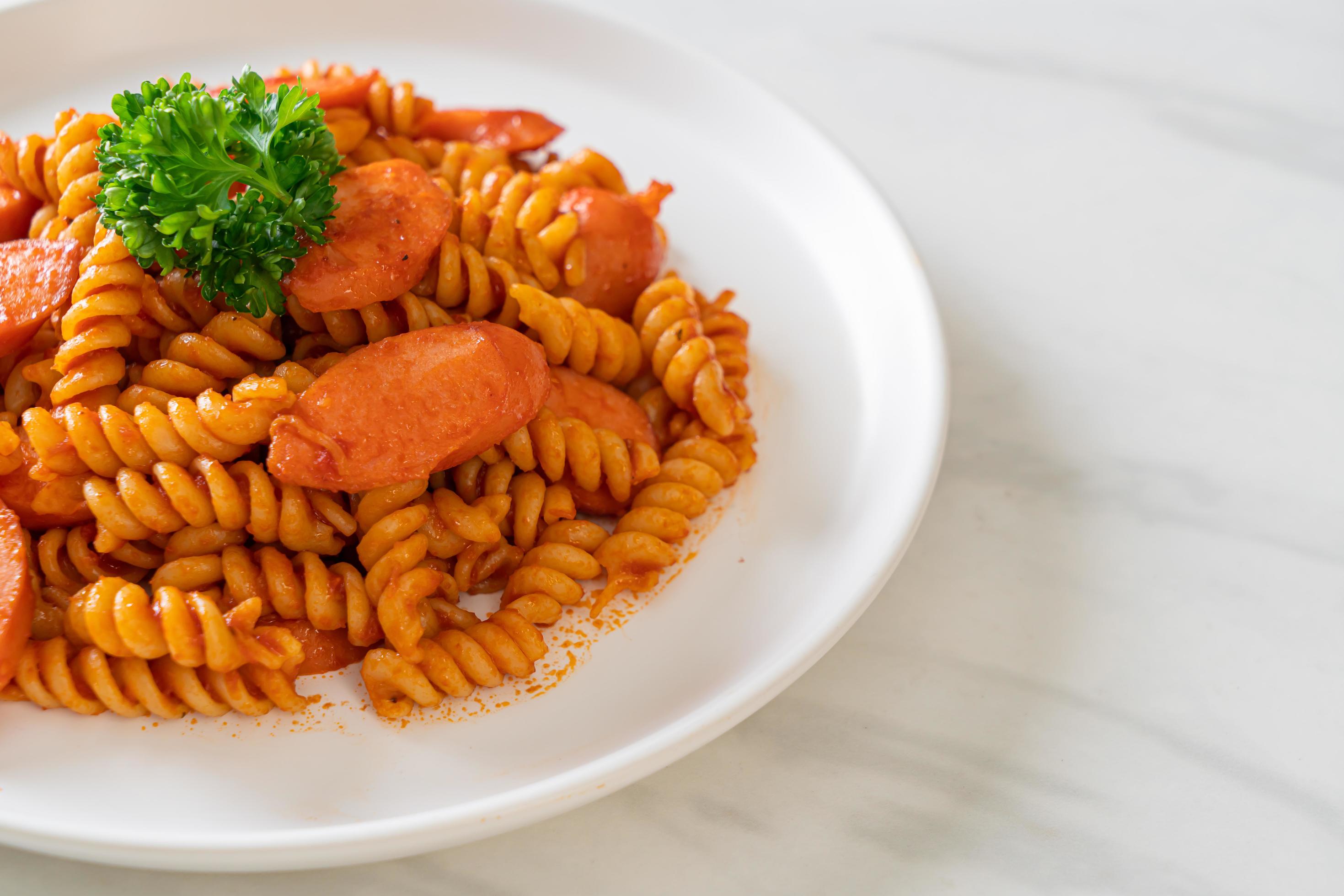 Spiral or spirali pasta with tomato sauce and sausage – Italian food style Stock Free