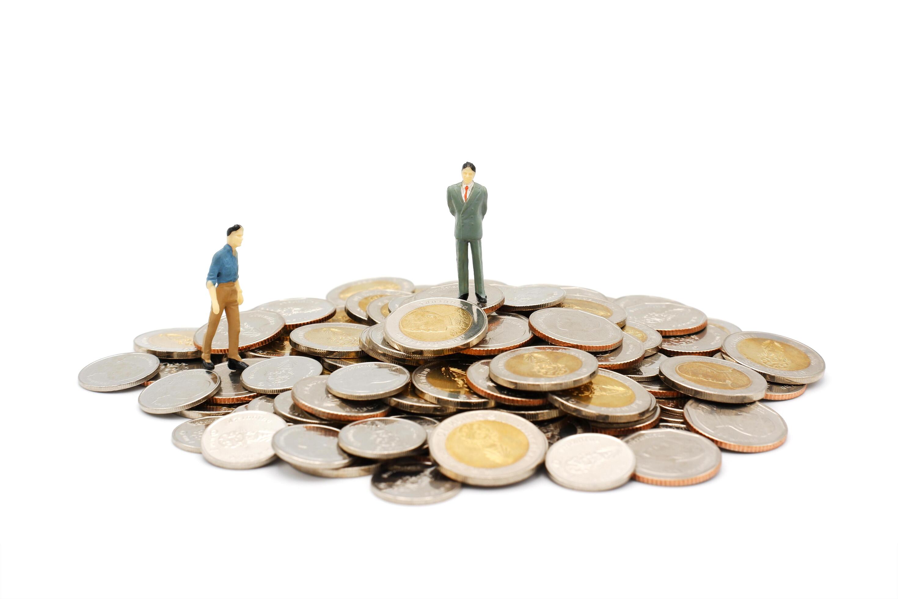 Two miniature people walking and standing on pile of new Thai Baht coins, isolated on white background. Business and finance concept. Stock Free