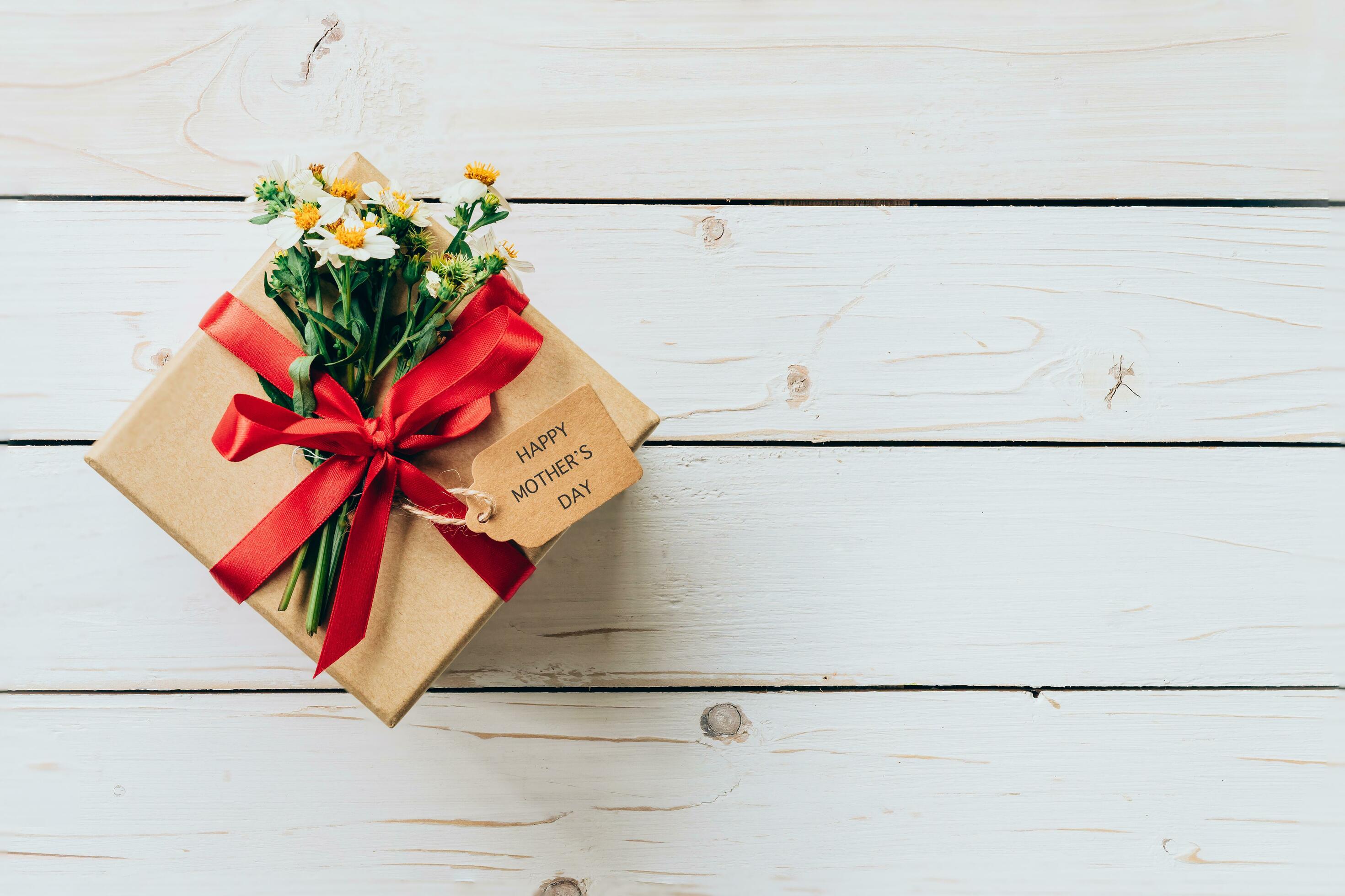 Brown gift box and flower on wood table present, mother’s day concept. Stock Free